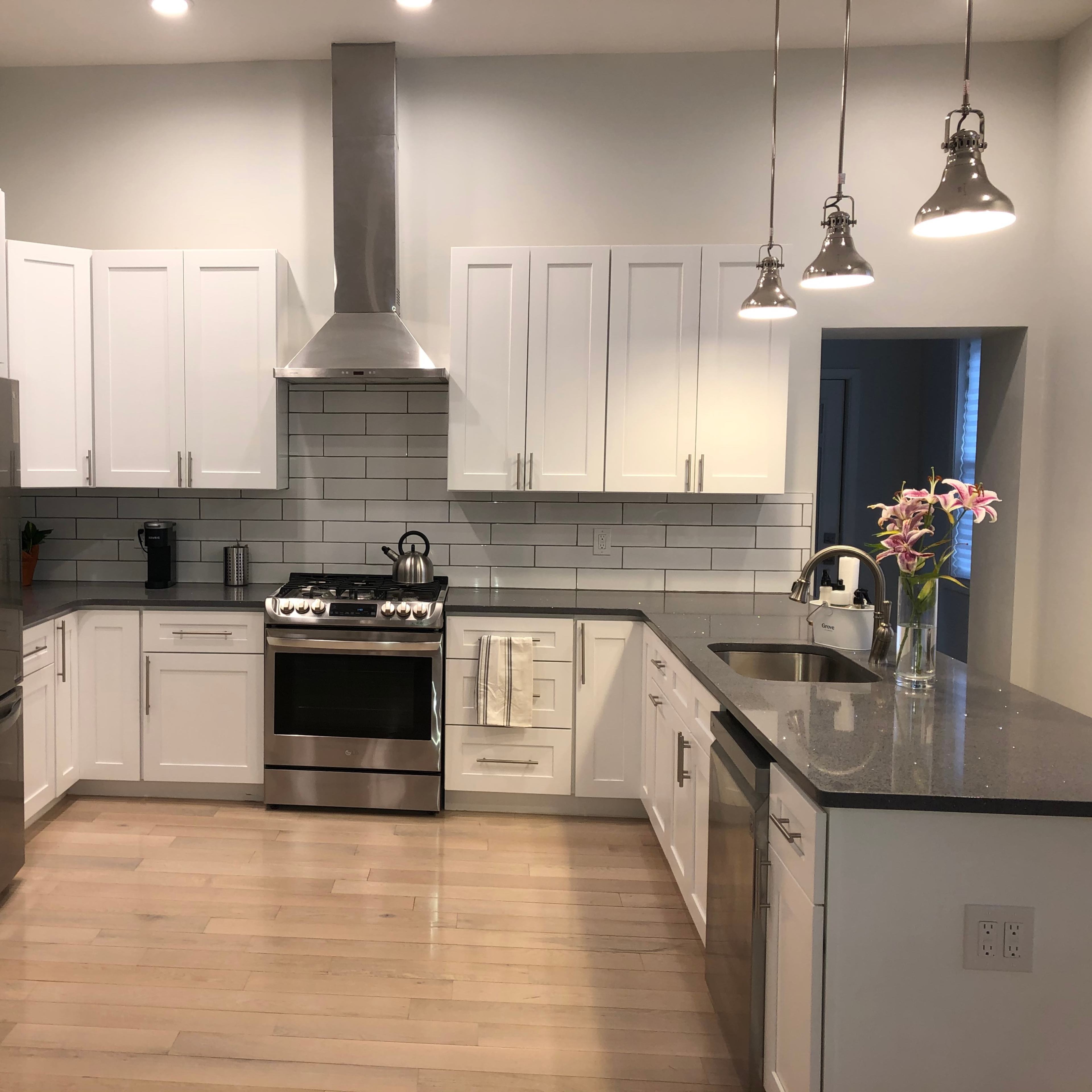A modern kitchen with white cabinetry, stainless steel appliances, and a gray countertop.