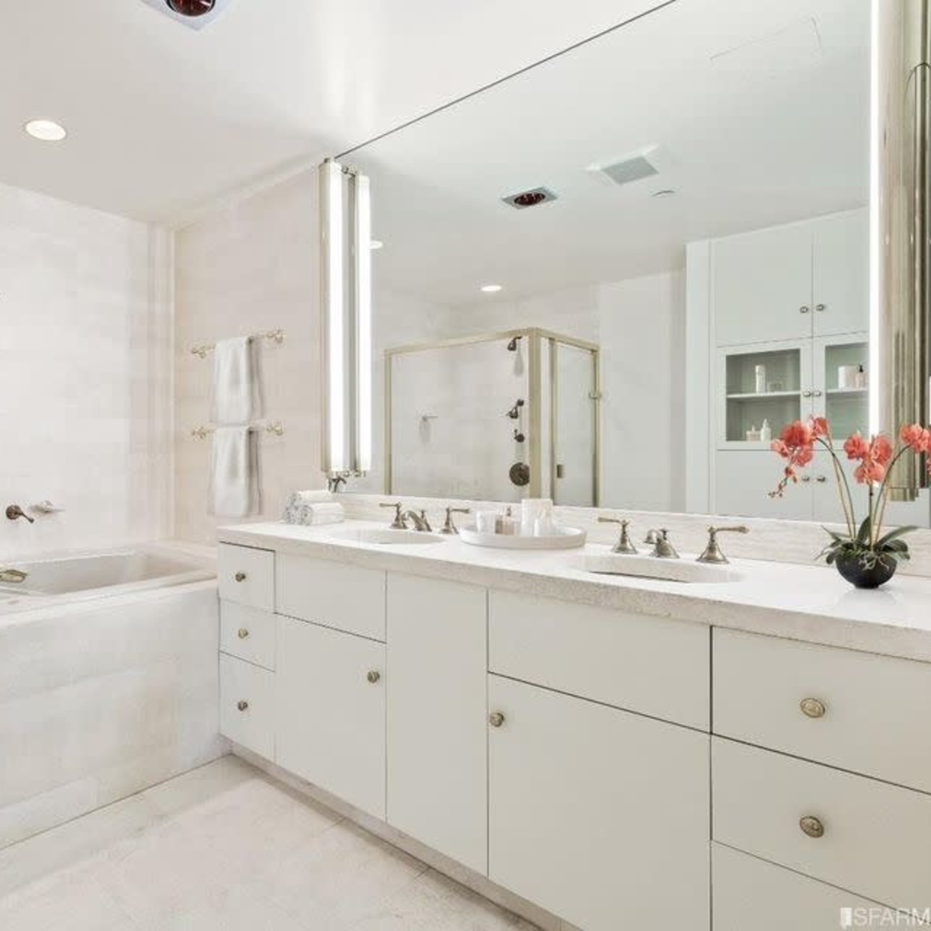 A modern bathroom featuring a dual sink vanity, a separate bathtub, and a large mirror with soft lighting.