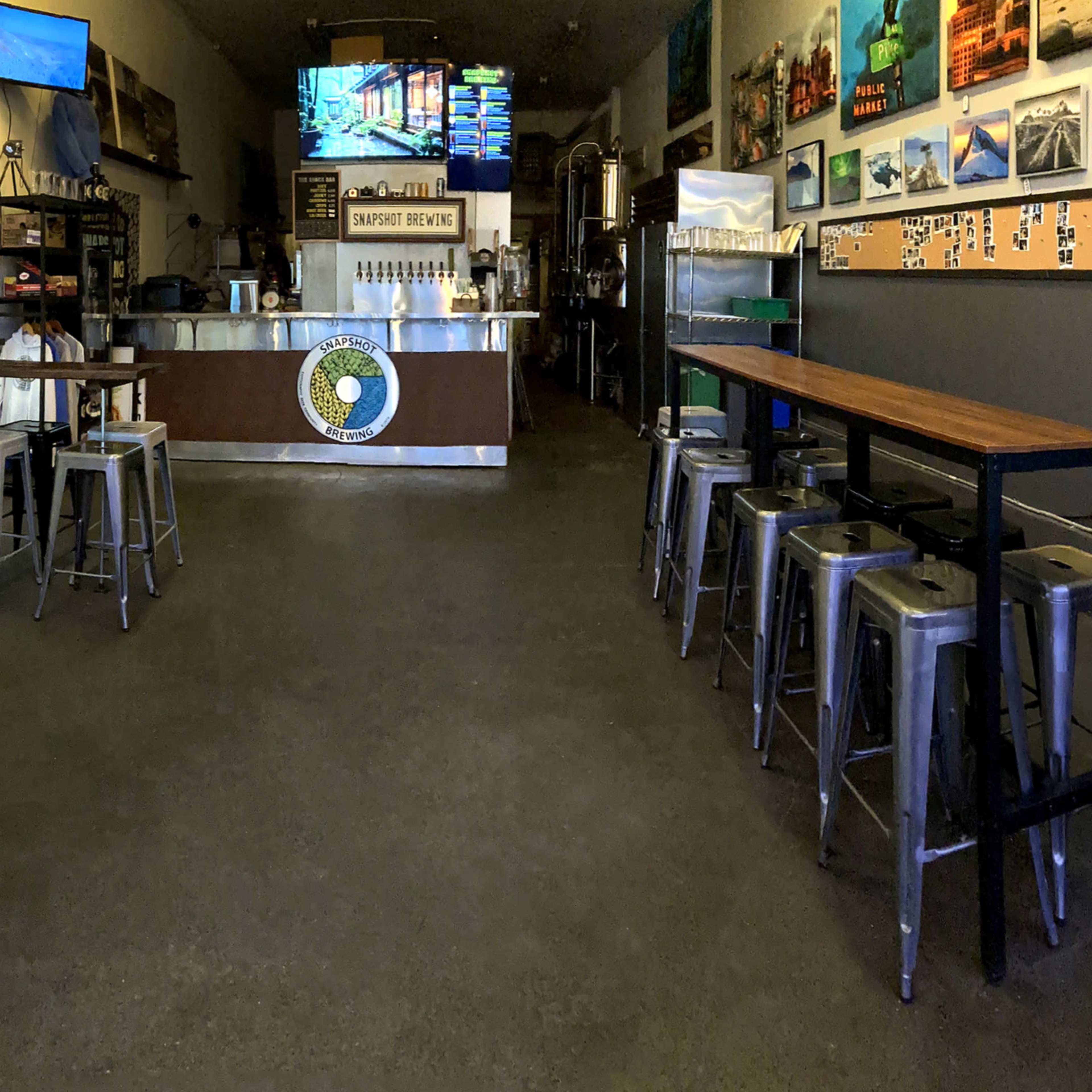 A bright, spacious café with a counter at the back, seating along both sides, and various artworks displayed on the walls.