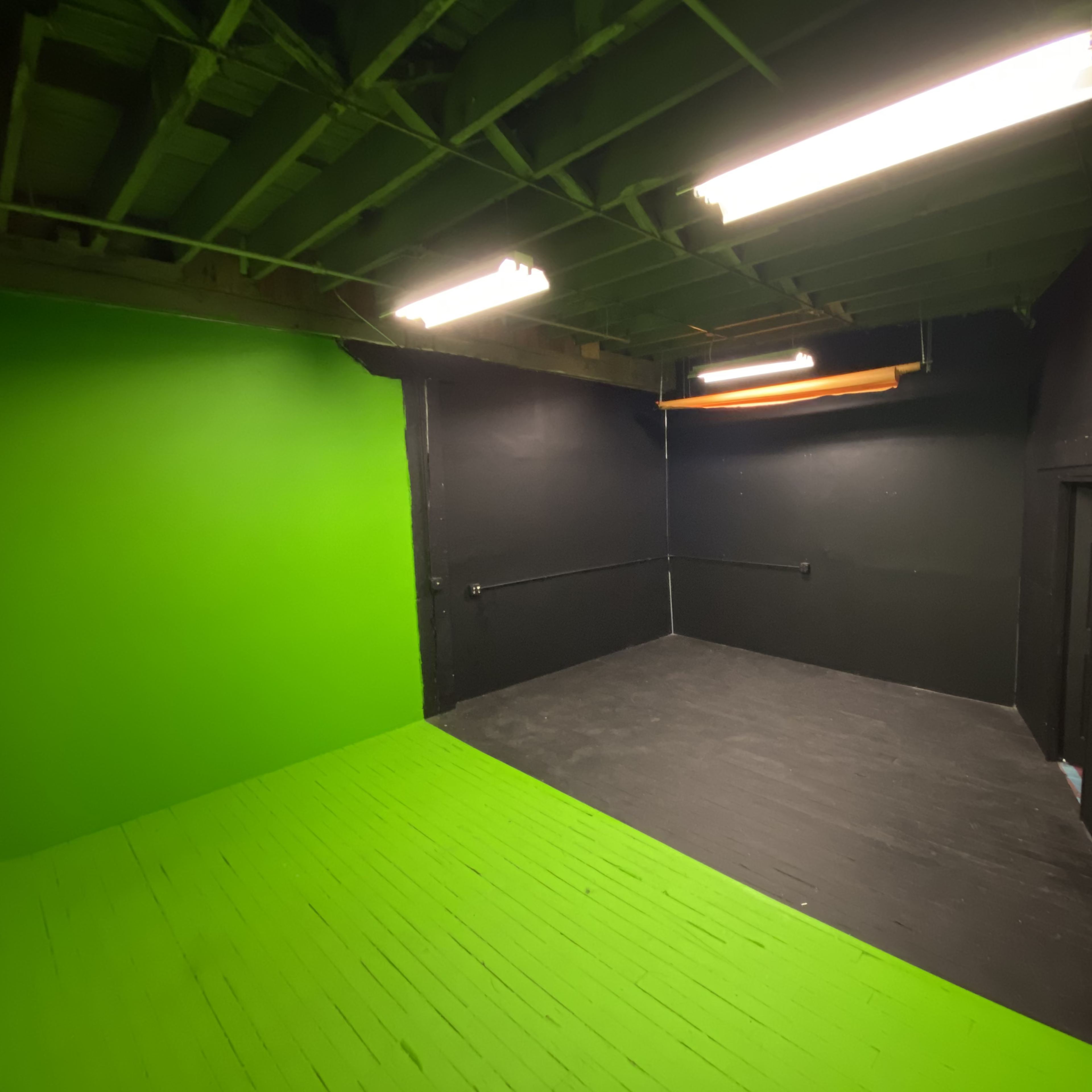 An empty room with one green wall and black walls and floor.