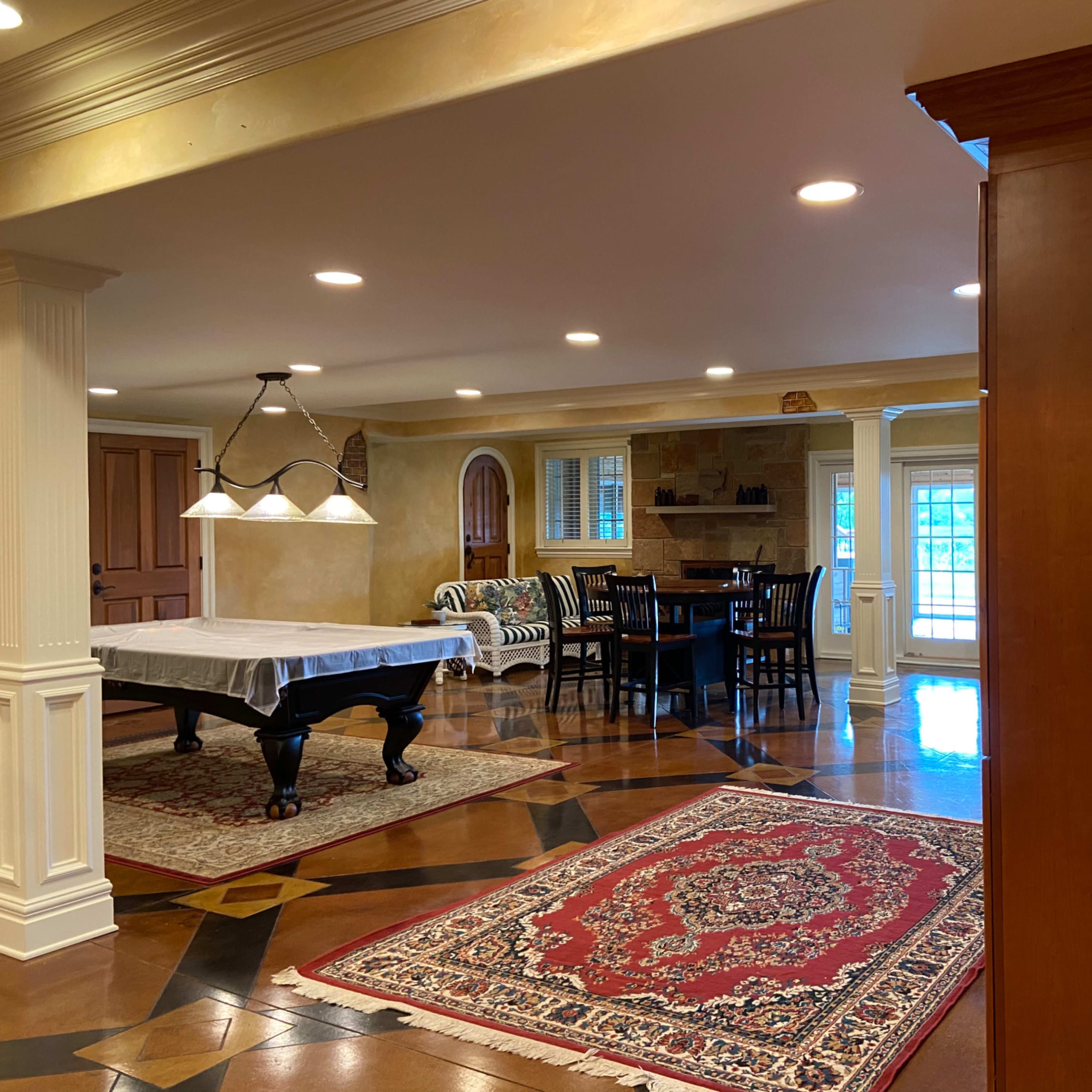 A spacious interior room with a pool table, dining area, and patterned rugs.