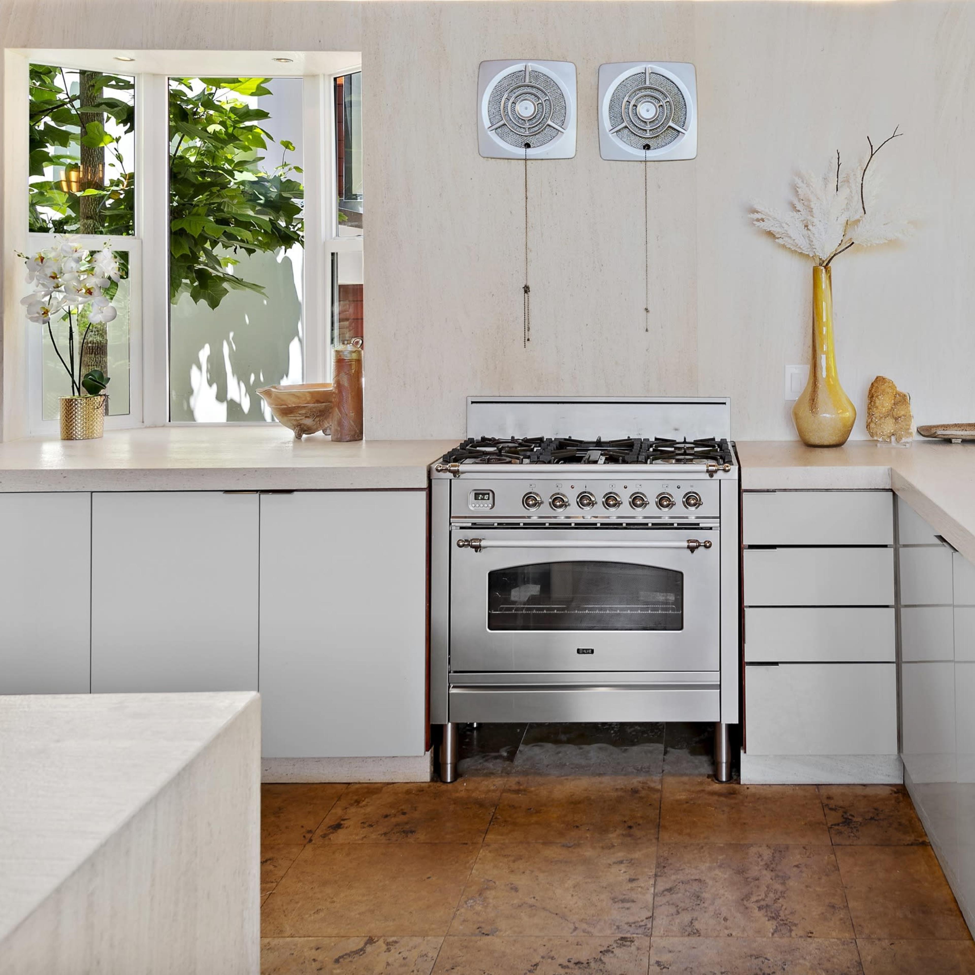 A modern kitchen features a stainless steel stove, white cabinetry, and a large island with a minimalist design.