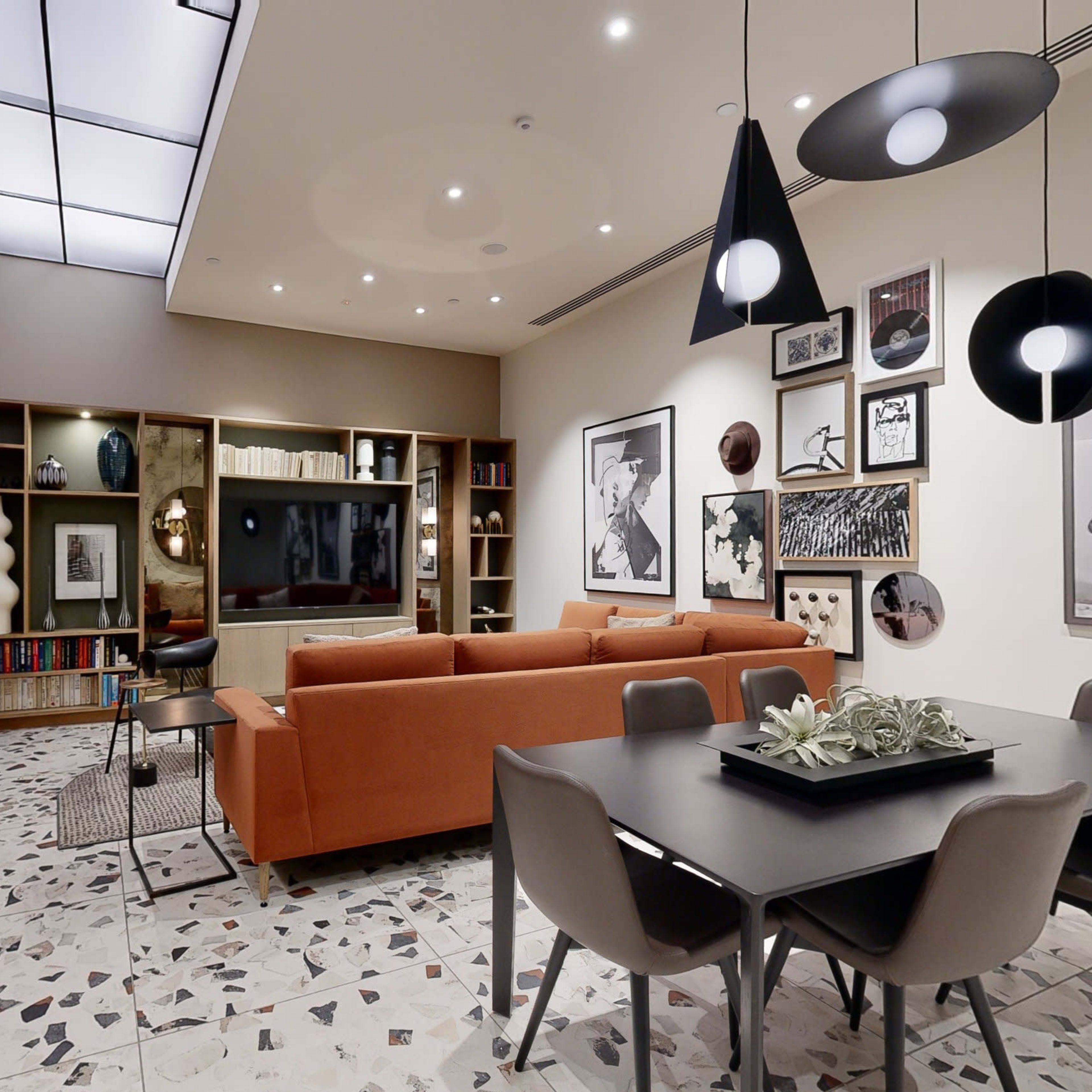 A modern living room and dining area with a sectional sofa, dining table, and various decorative elements against a backdrop of a patterned floor.