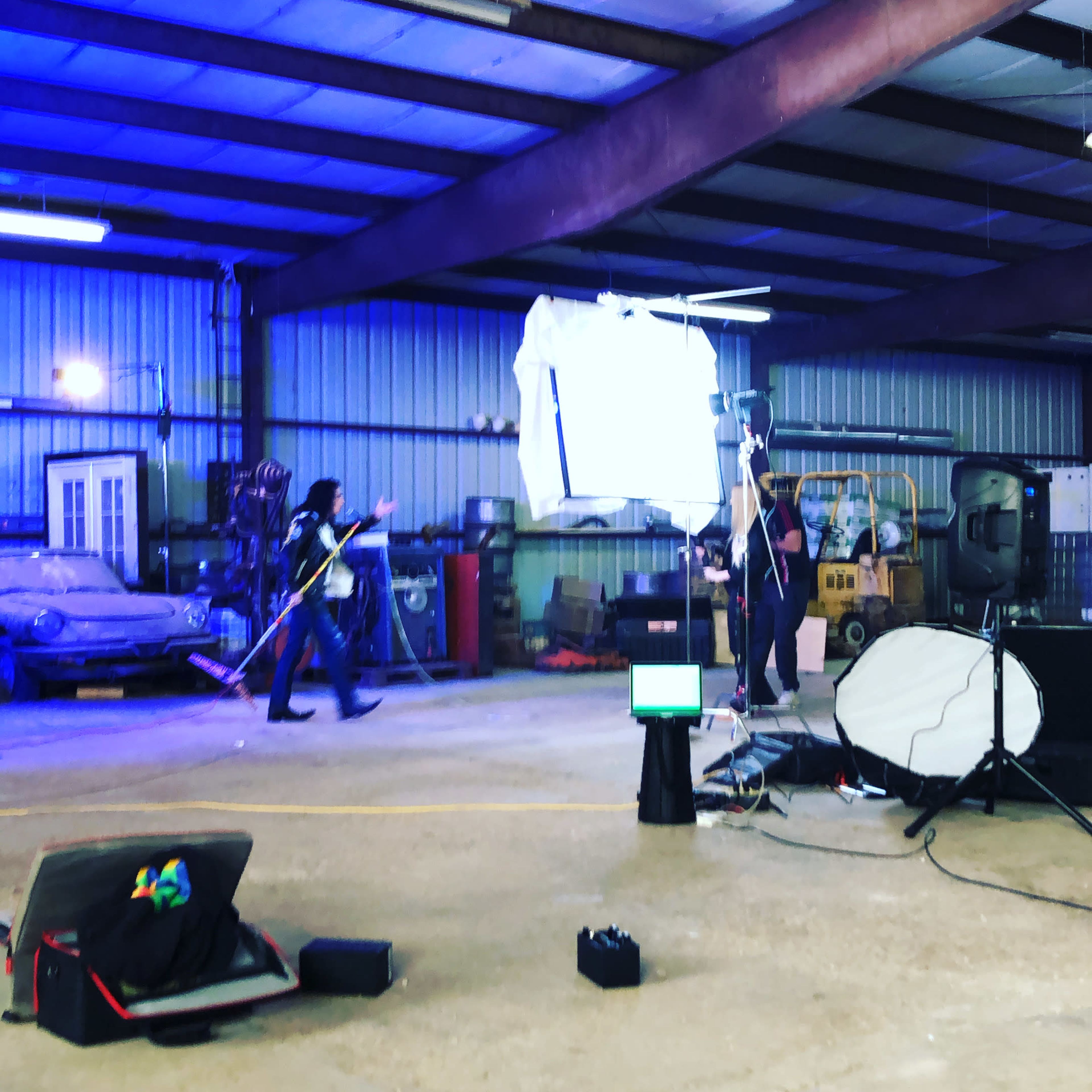 A band performs in a large industrial space, with musical equipment set up and stage lights illuminating the area.