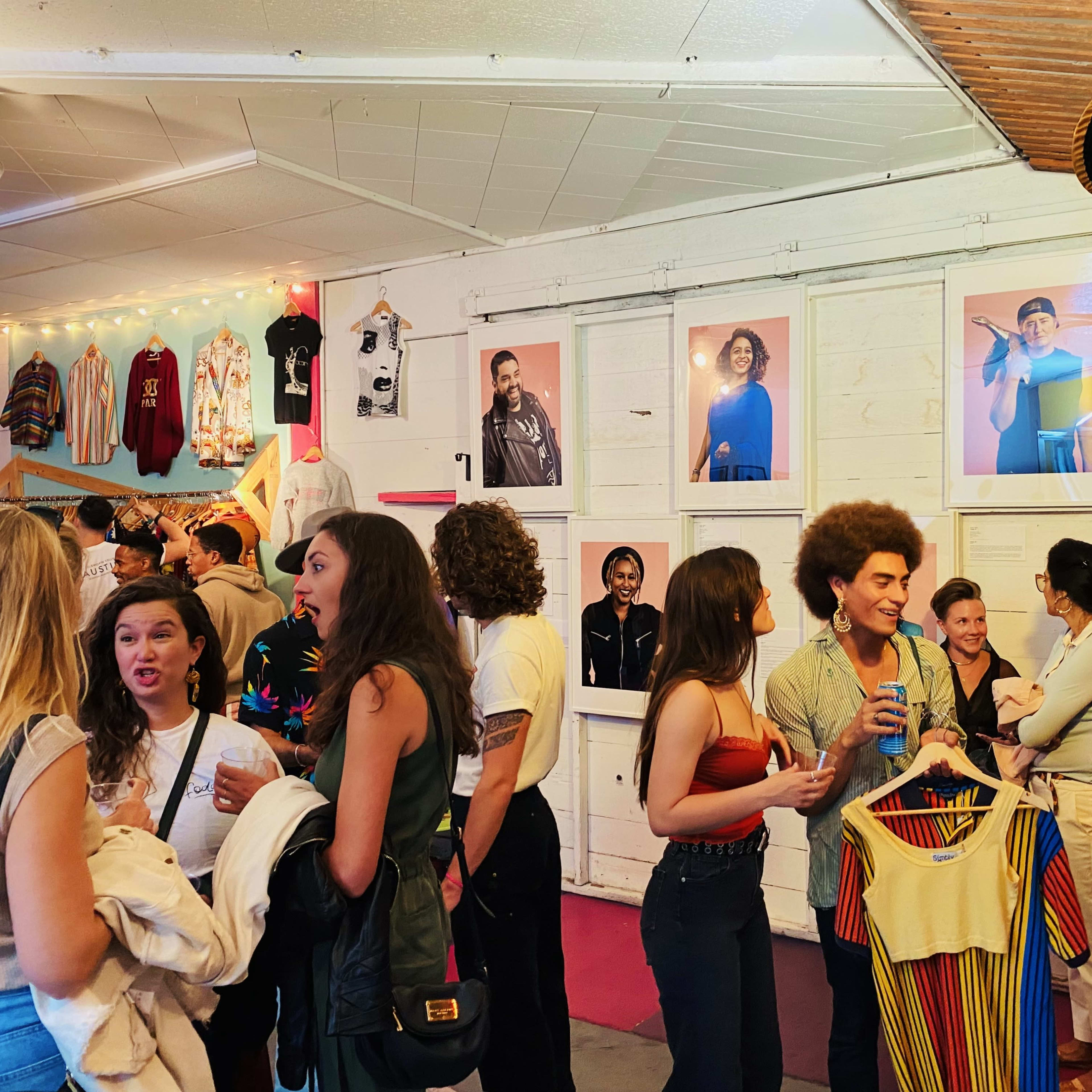 A group of people socializes in a gallery displaying framed photographs on the walls.