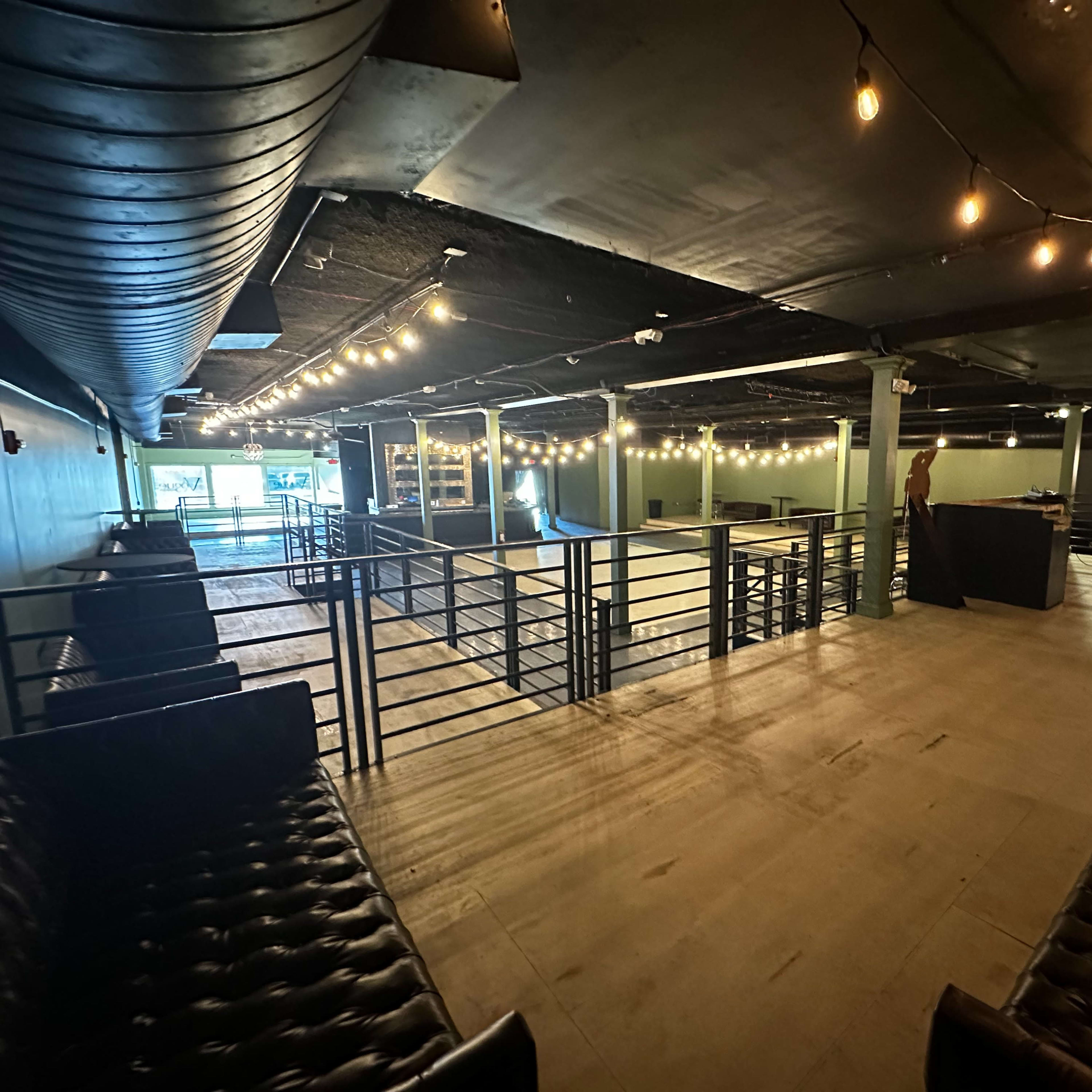 An empty, well-lit indoor venue with string lights and seating areas arranged around a central space.