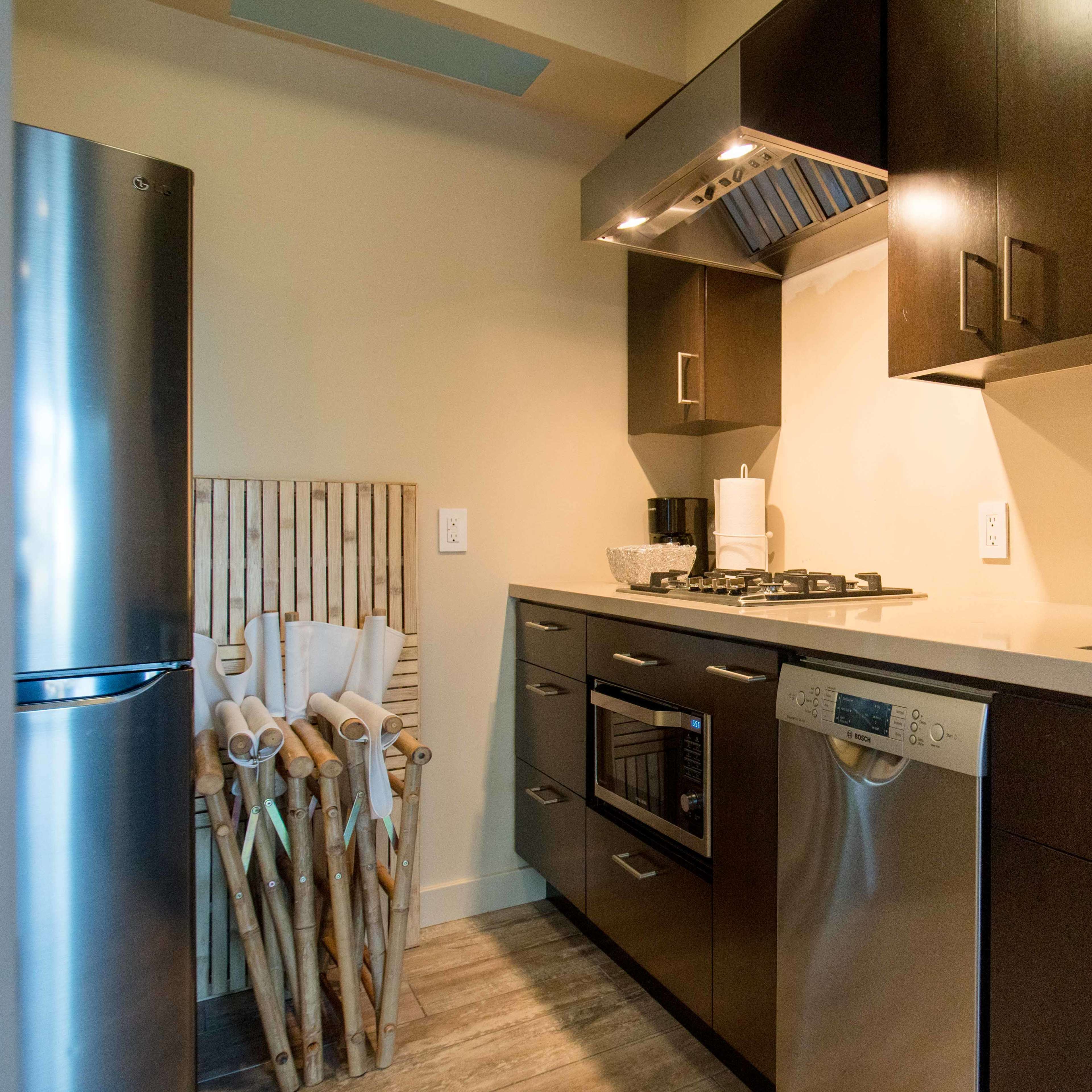 A modern kitchen featuring dark cabinetry, stainless steel appliances, and a countertop with a sink and stove.