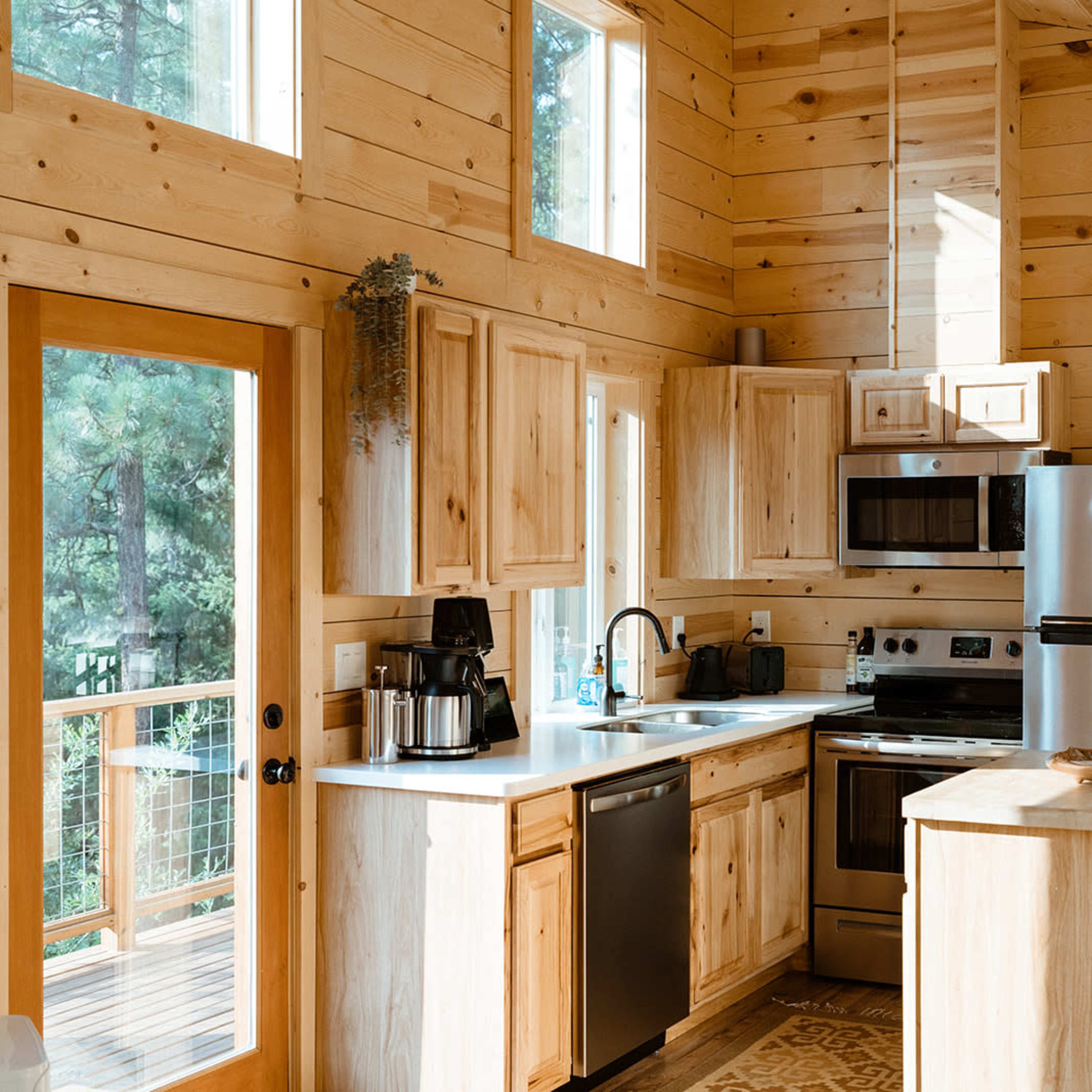 A modern kitchen with wooden walls, stainless steel appliances, and a countertop island with bar stools.