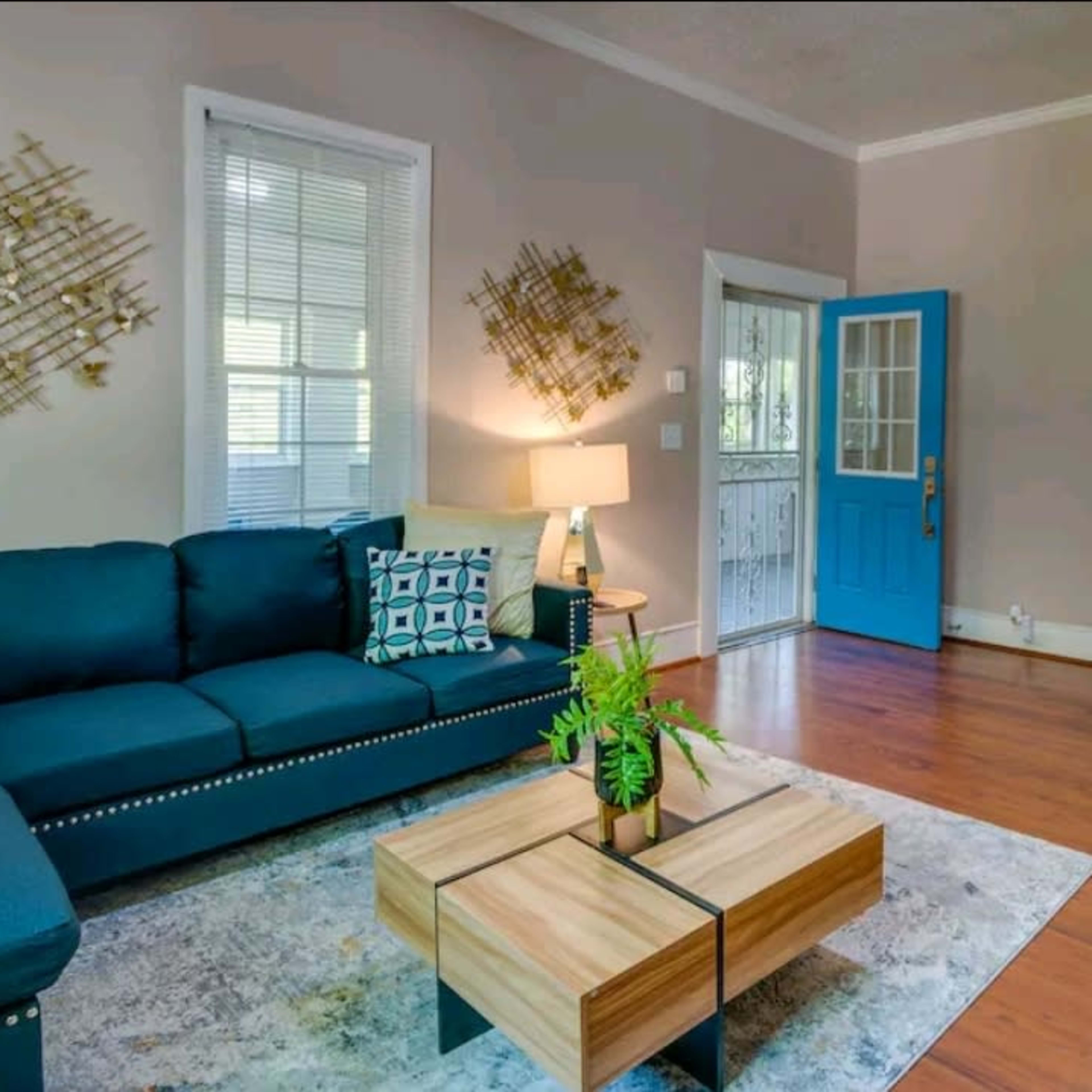 A living room featuring a blue couch, a coffee table, and a bright blue front door.