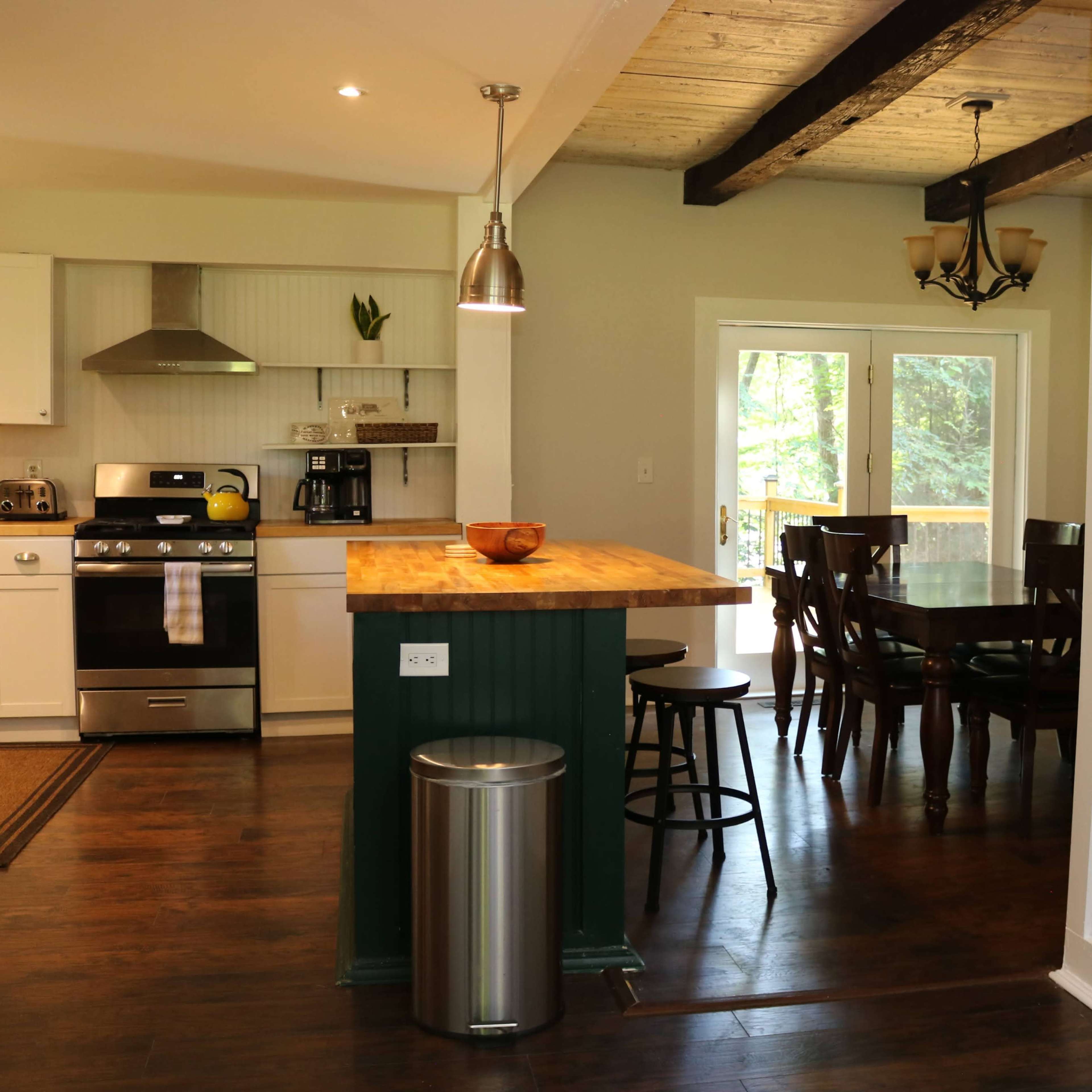 A modern kitchen with white cabinetry, a wooden island, and a dining area with a wooden table and chairs.