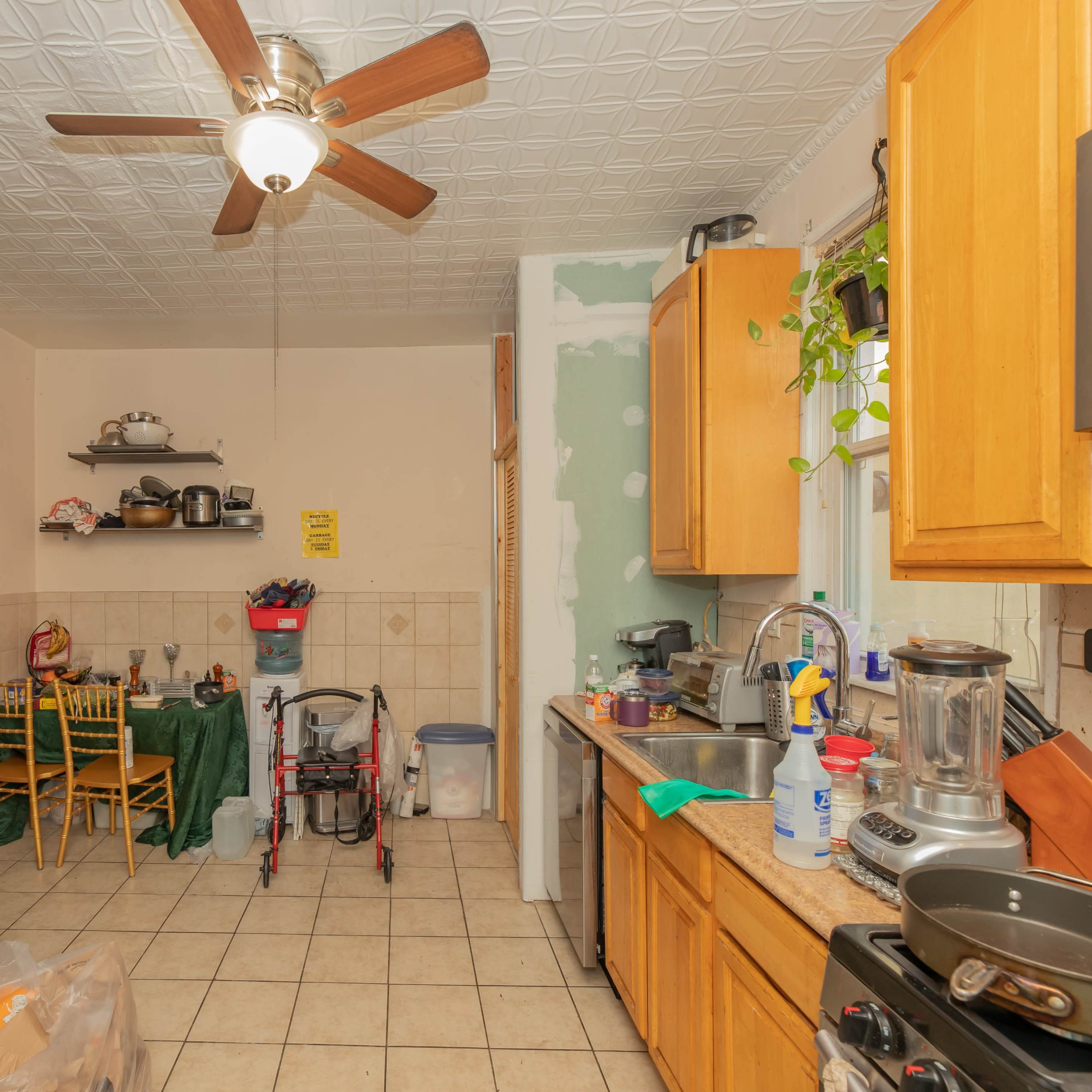 A kitchen with wooden cabinets, a ceiling fan, and a dining area featuring a table and chairs.