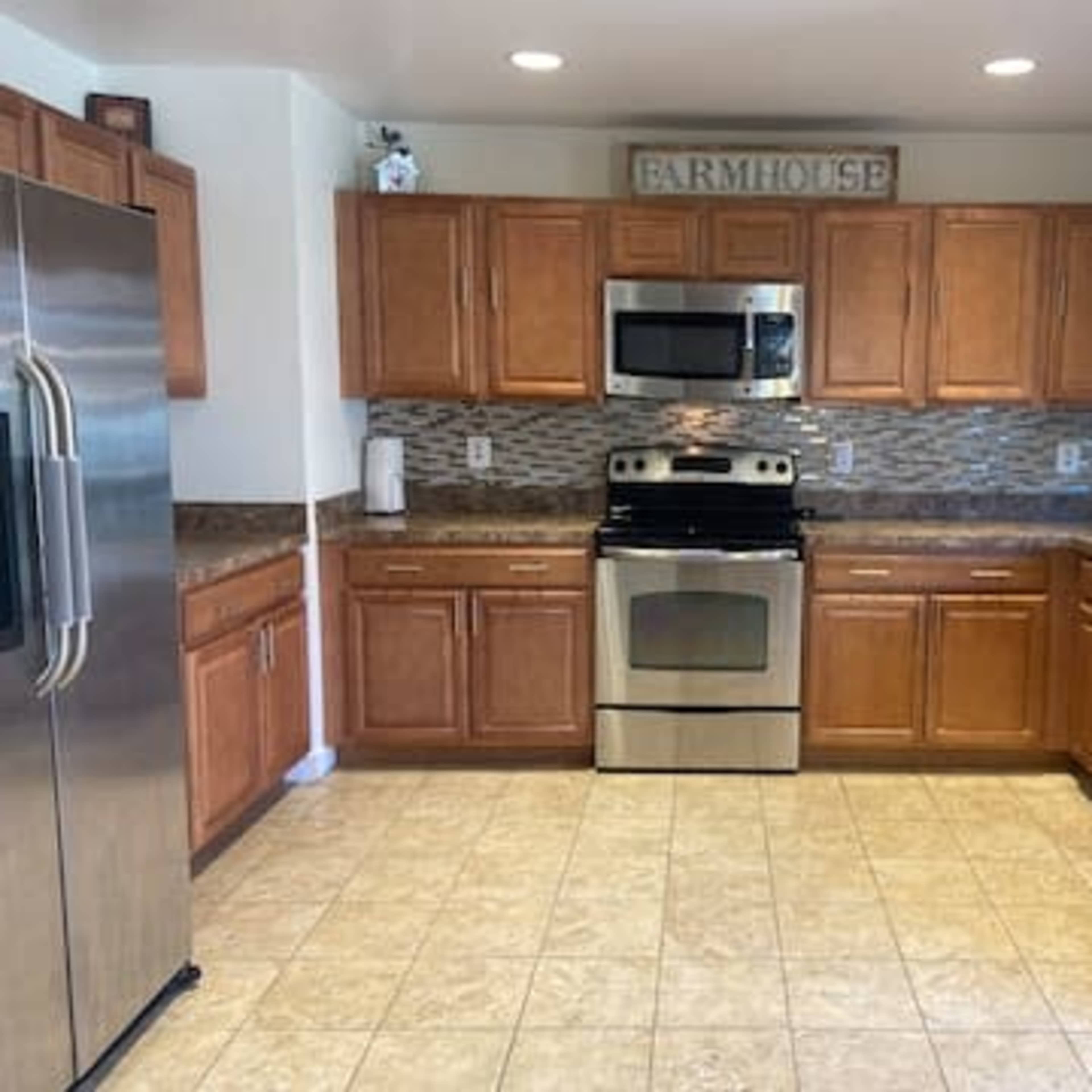 A modern kitchen features wooden cabinets, stainless steel appliances, and tiled flooring.