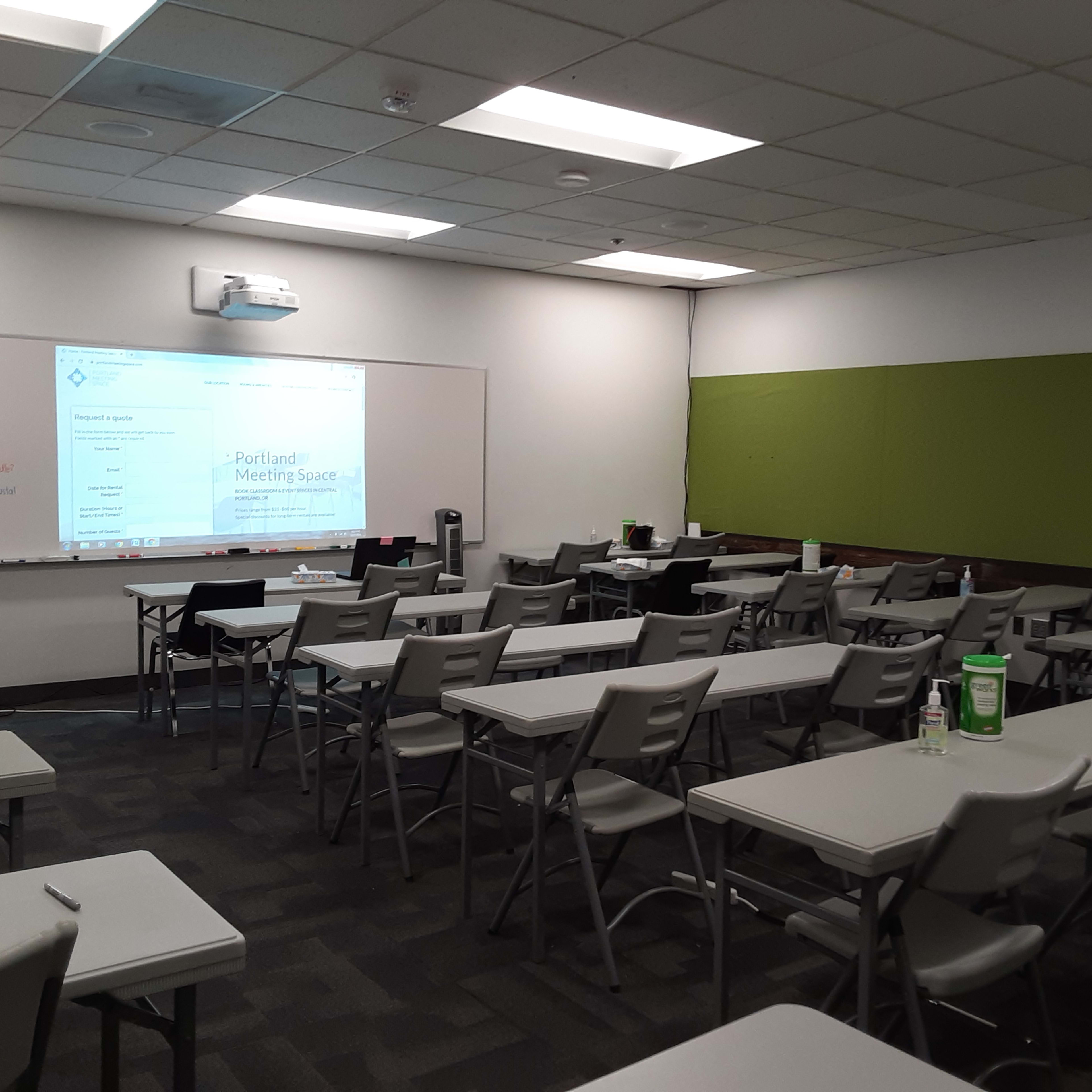 A classroom setting with arranged desks and a presentation screen at the front.