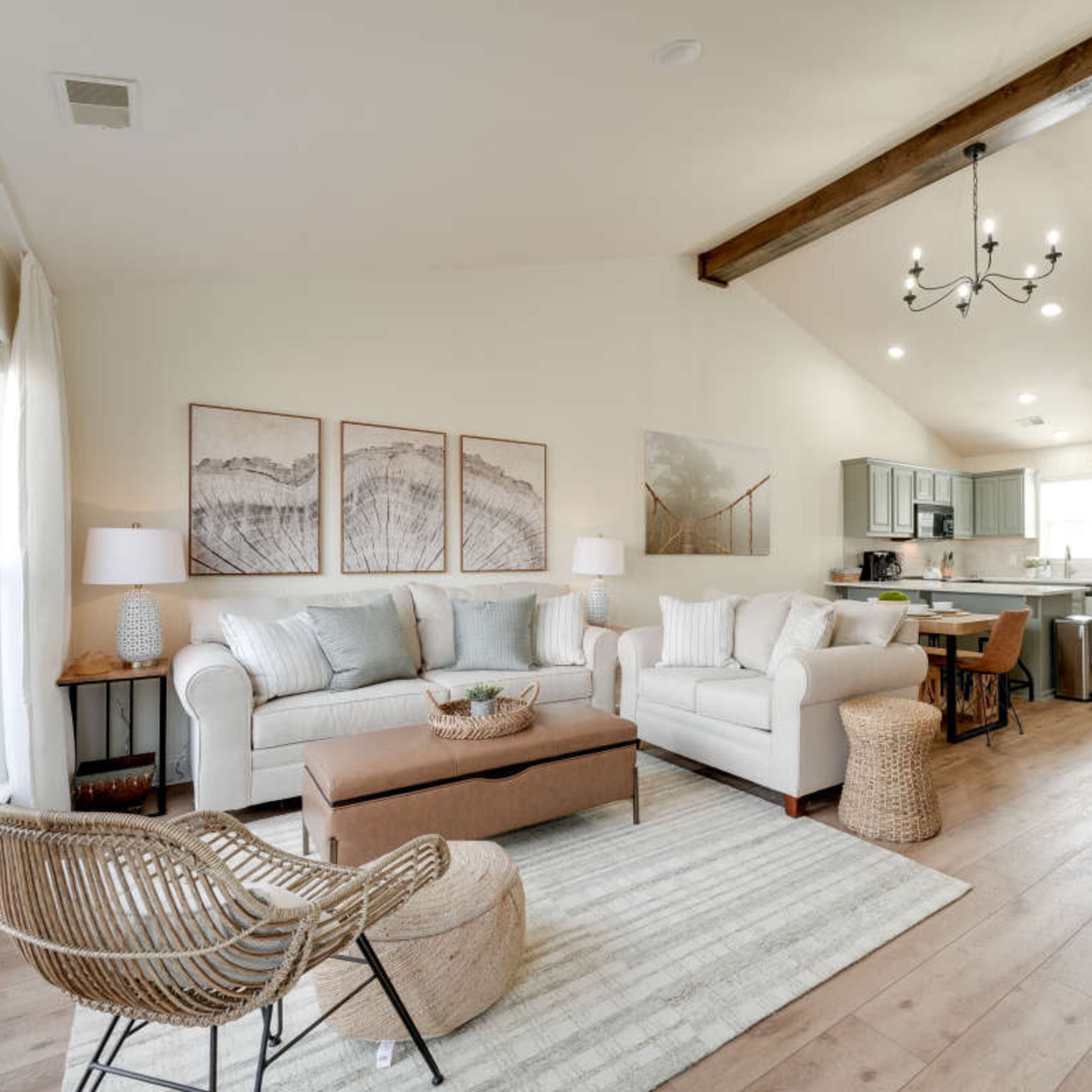 A spacious living area with a light-colored sofa, a wooden coffee table, and a dining space adjacent to a modern kitchen.