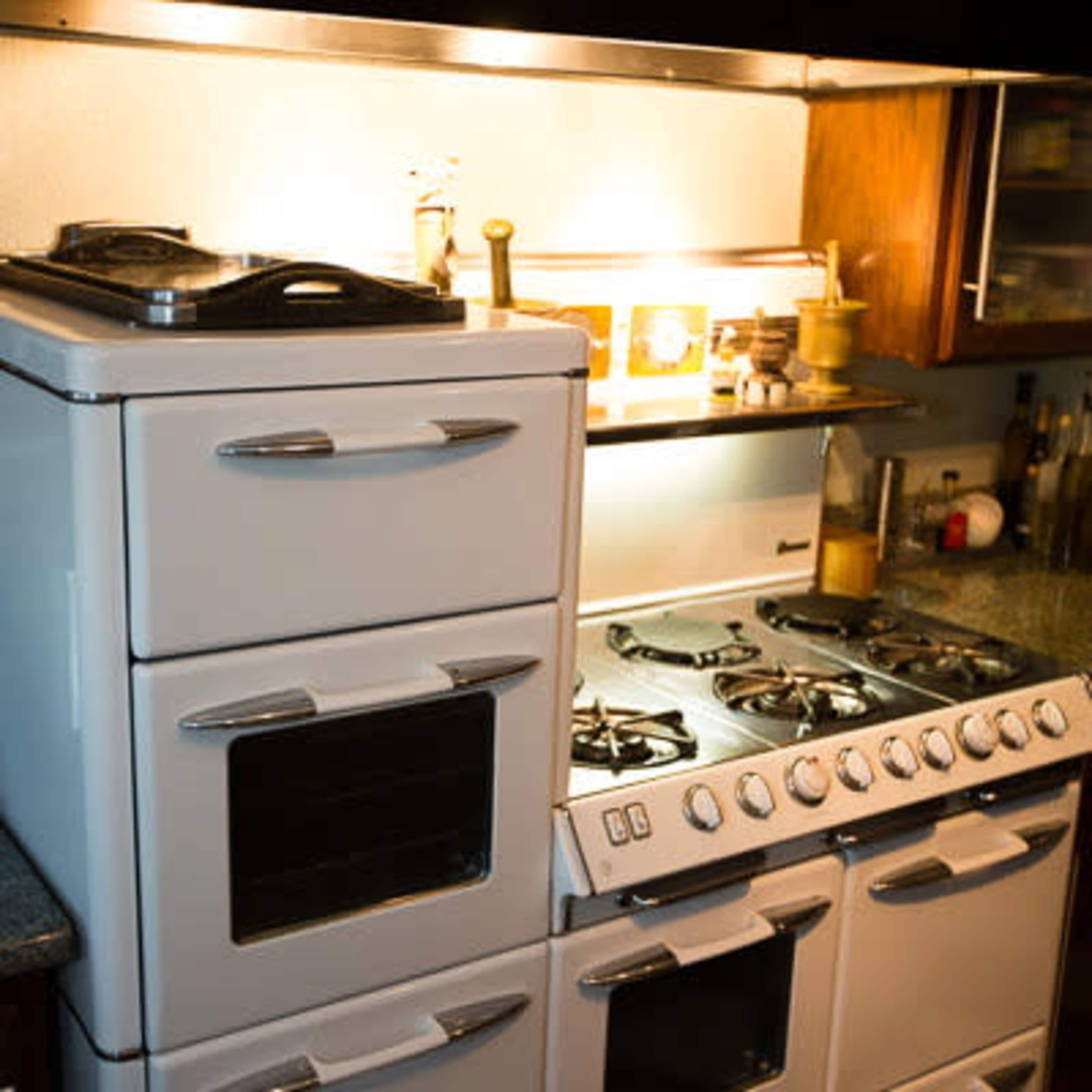 A retro-style kitchen stove and oven with multiple burners and compartments set against a dark countertop.