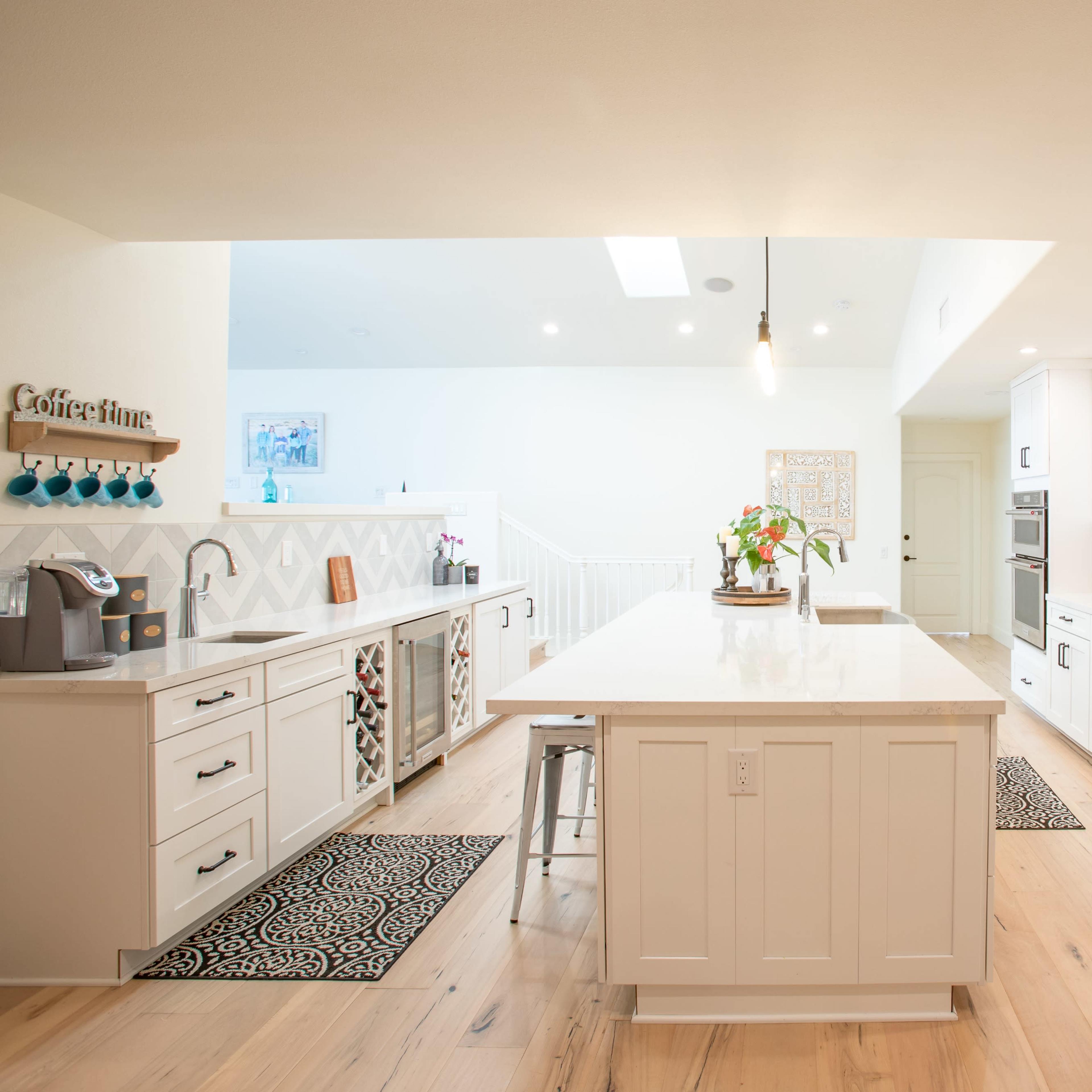 A modern kitchen features white cabinetry, a central island with a light countertop, and stainless steel appliances.