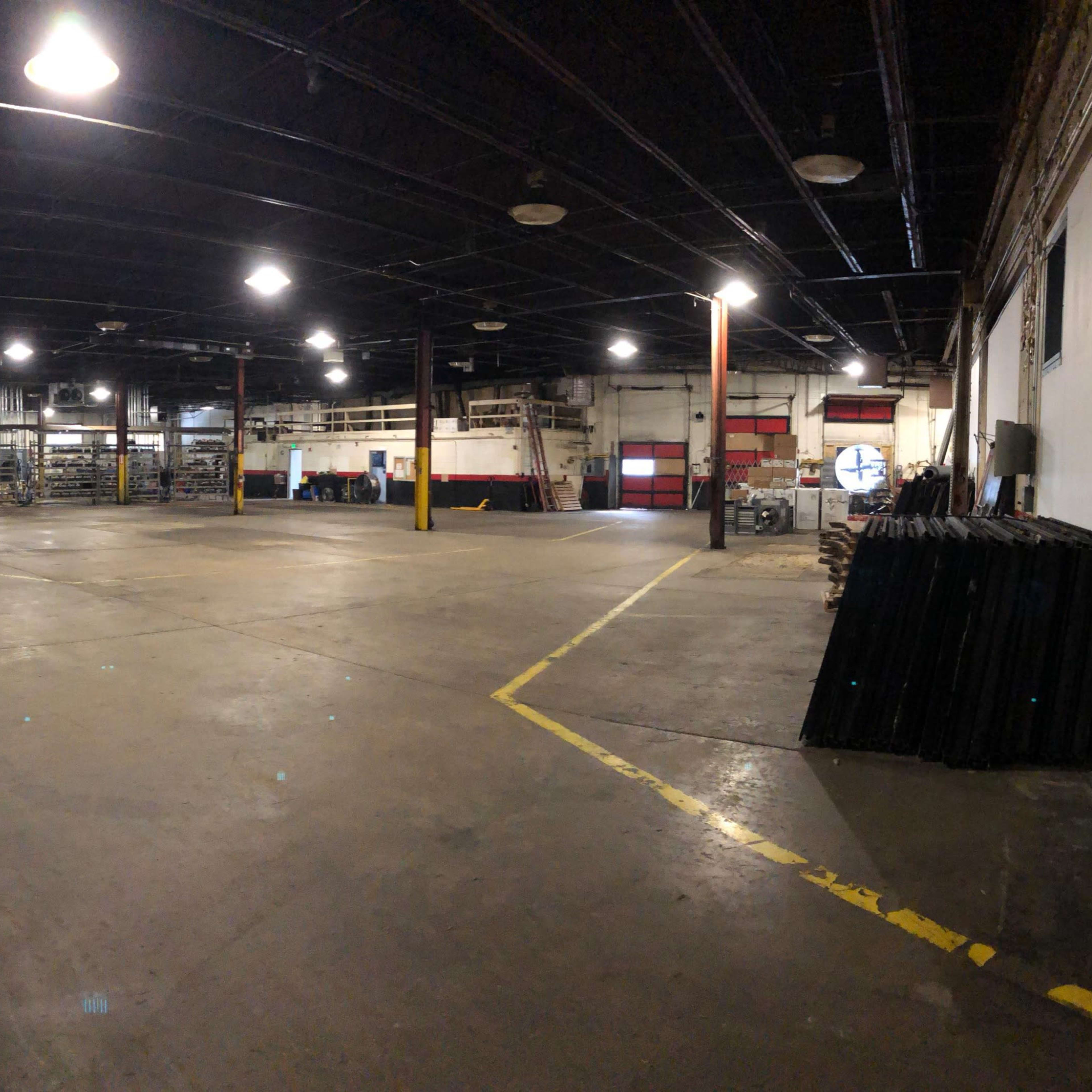 A large, empty industrial warehouse space with exposed beams and concrete floors.