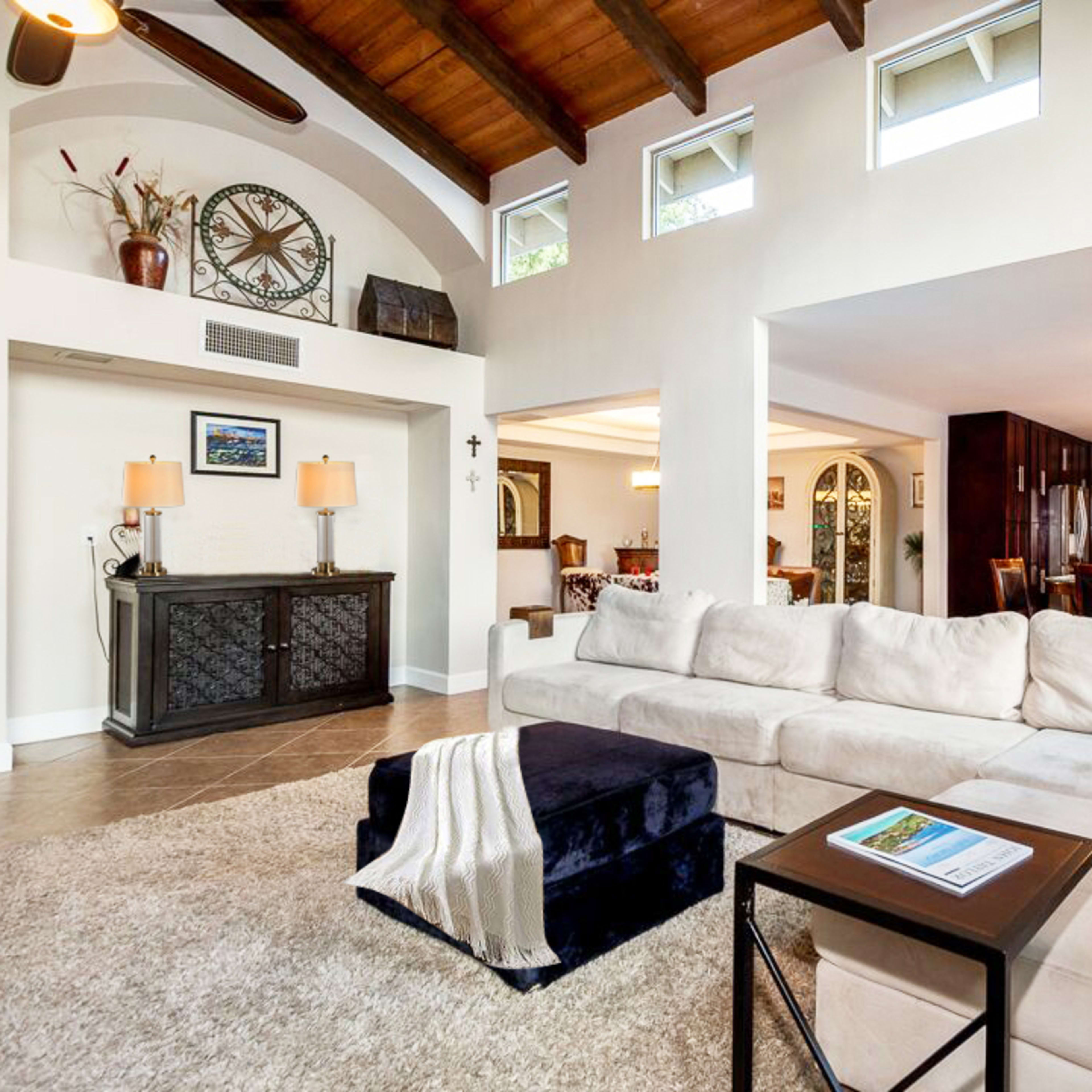 A spacious living room with a large sectional sofa, a coffee table, and an open layout leading to a dining area and kitchen.