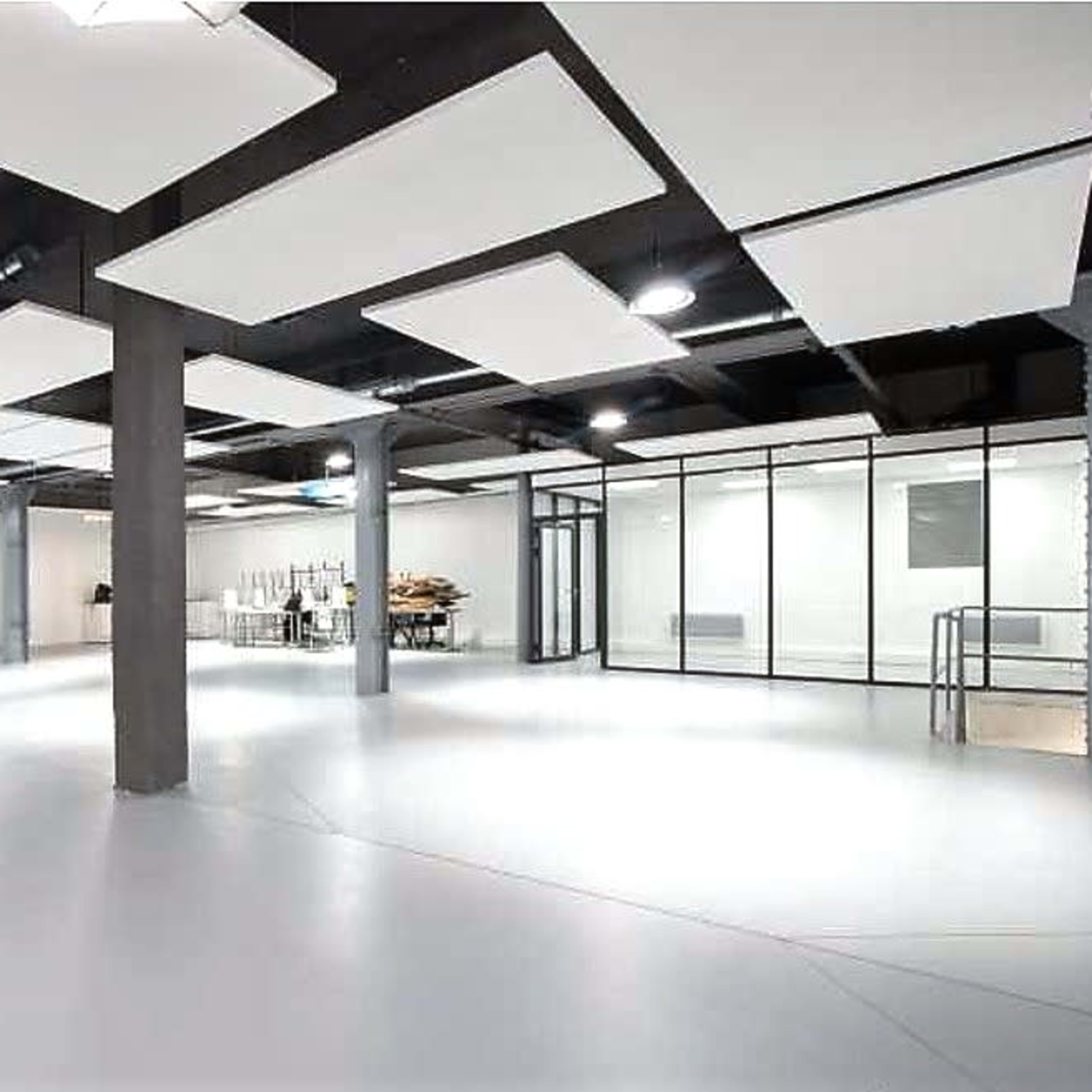 A spacious, empty interior with white walls, a smooth floor, and several overhead light fixtures.