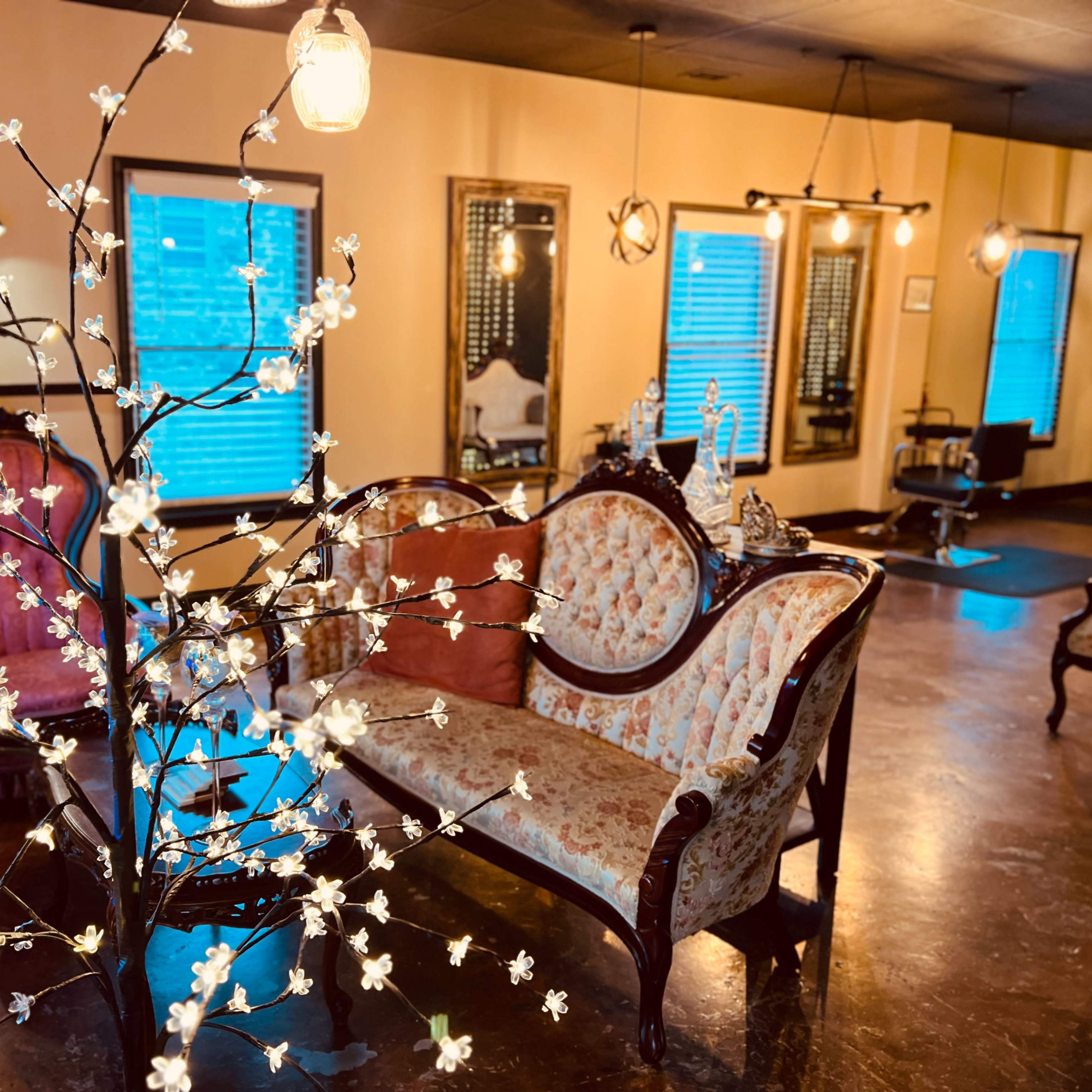 A vintage-style parlor with a floral-decorated tree, ornate seating, and warm ambient lighting.