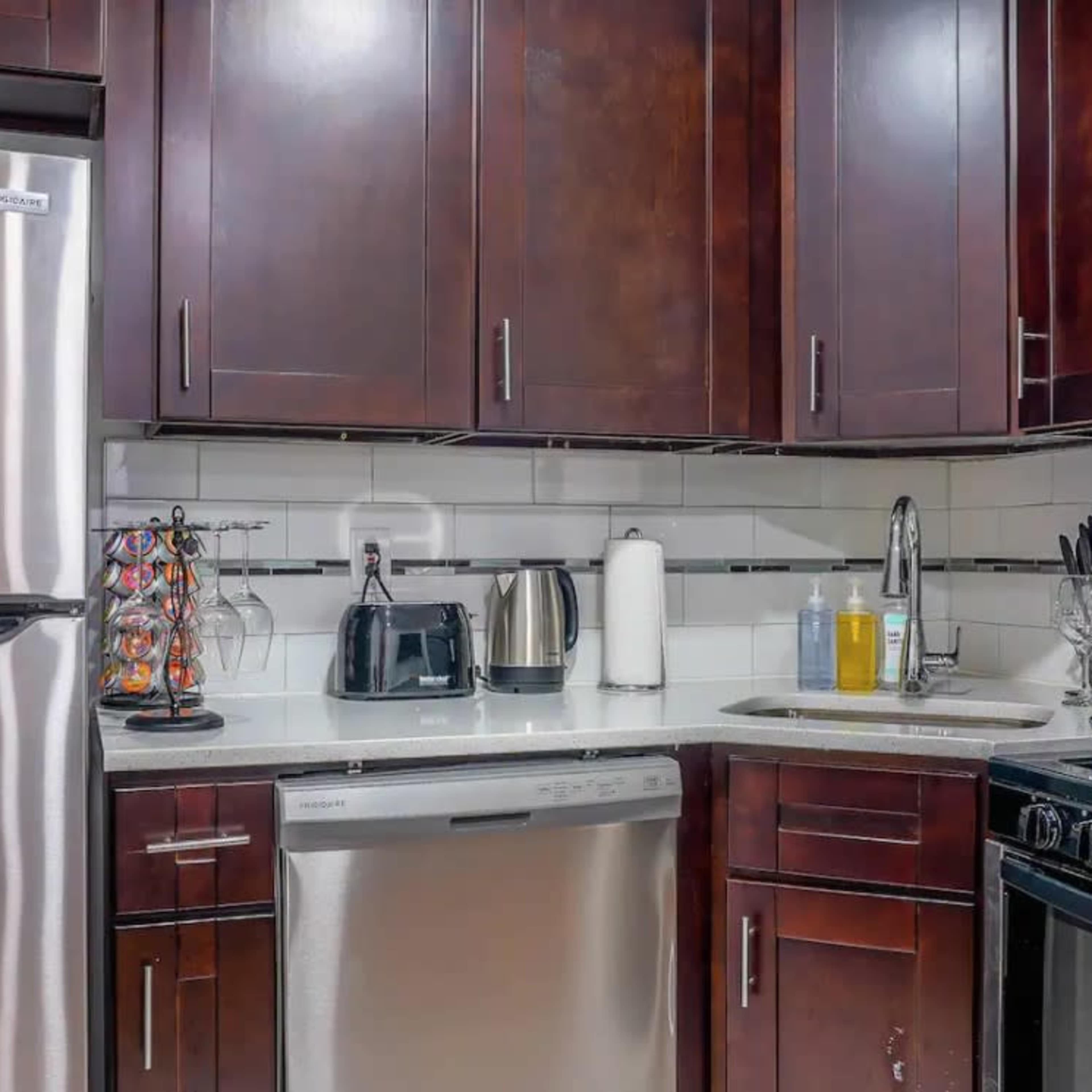 A modern kitchen featuring stainless steel appliances, dark wooden cabinetry, and a white countertop.