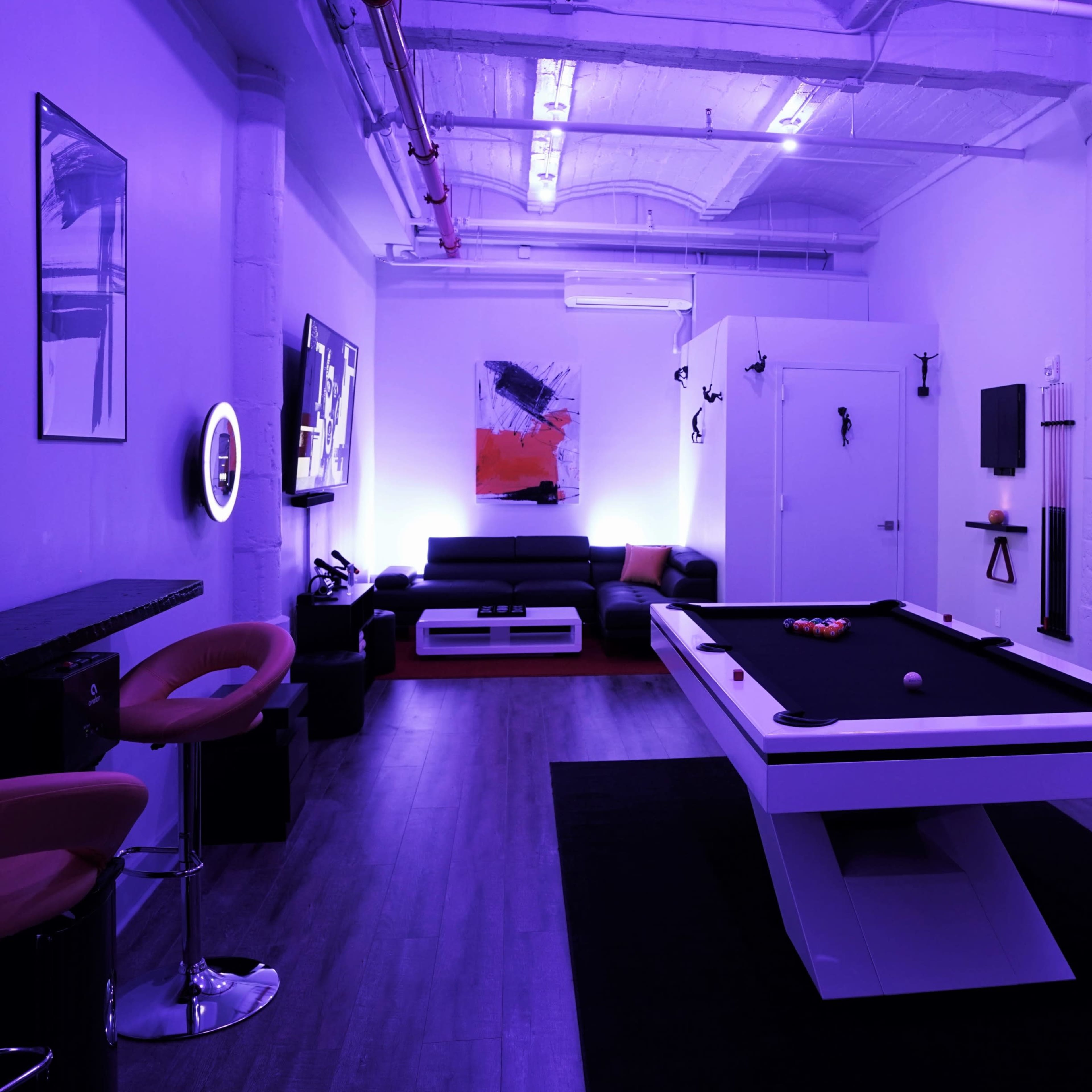 The room features a modern billiards table surrounded by seating, ambient lighting, and a mural on the wall.