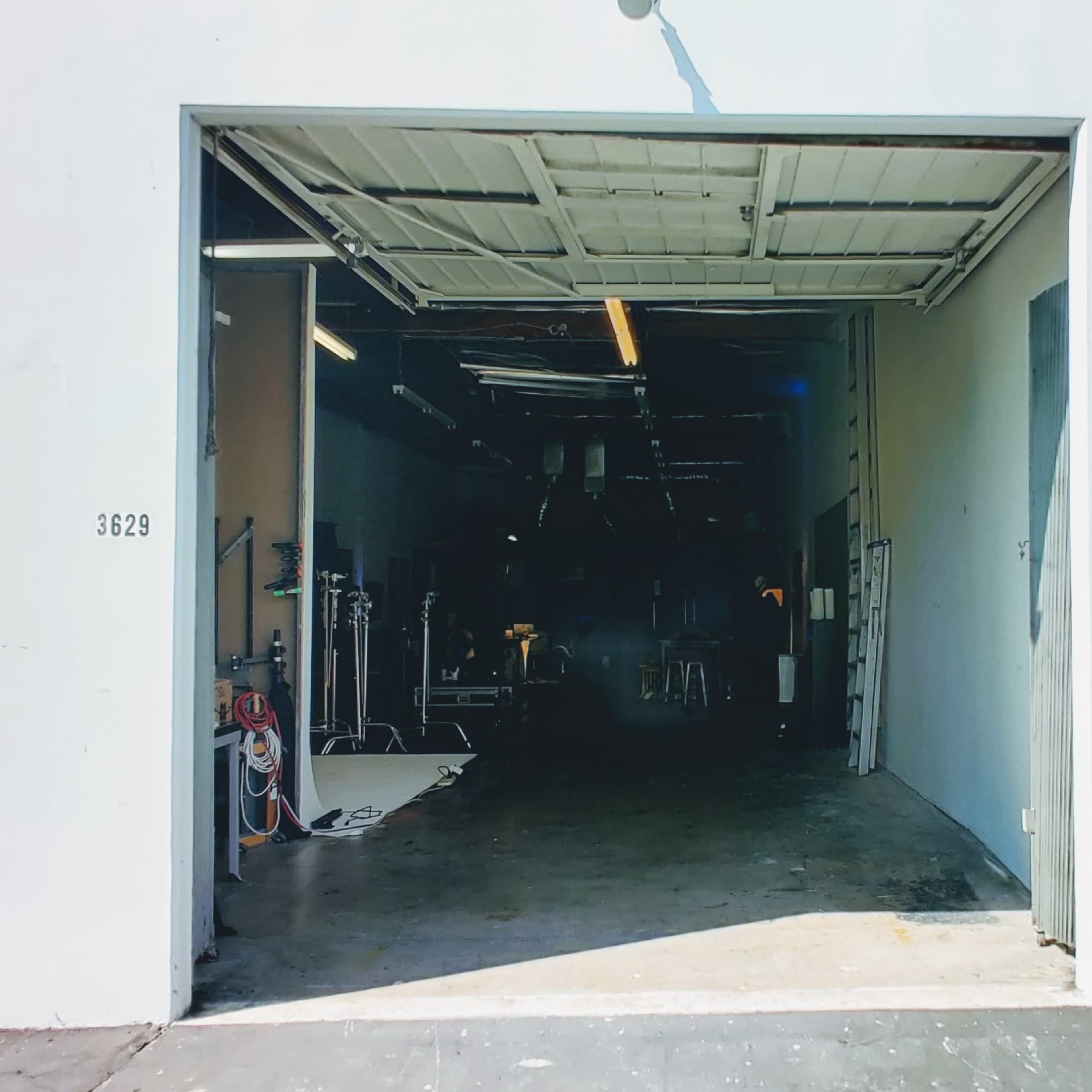 The open entrance of a warehouse with two large doors, revealing a dimly lit interior and equipment visible inside.