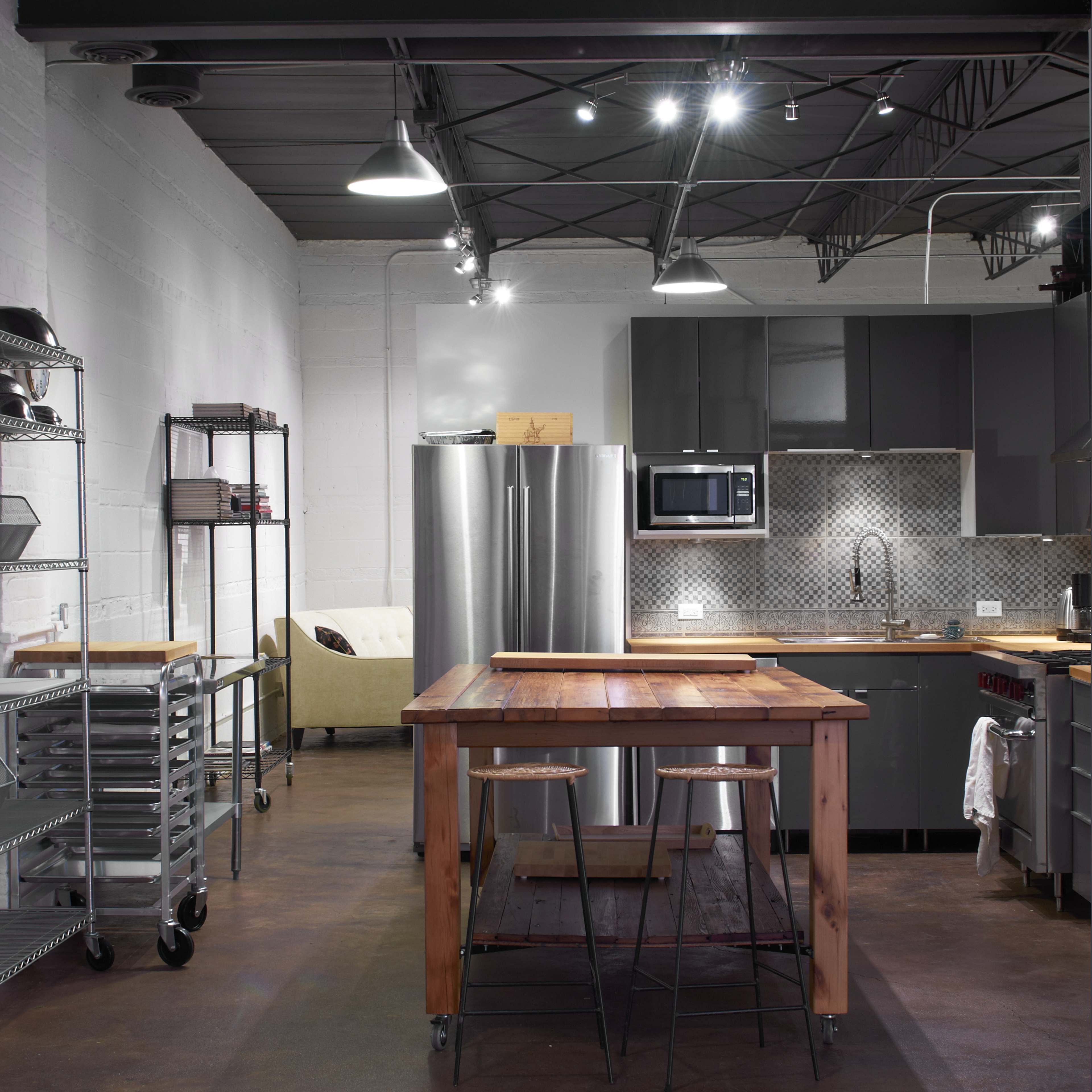 A modern kitchen with stainless steel appliances, a wooden island, and industrial-style shelving.