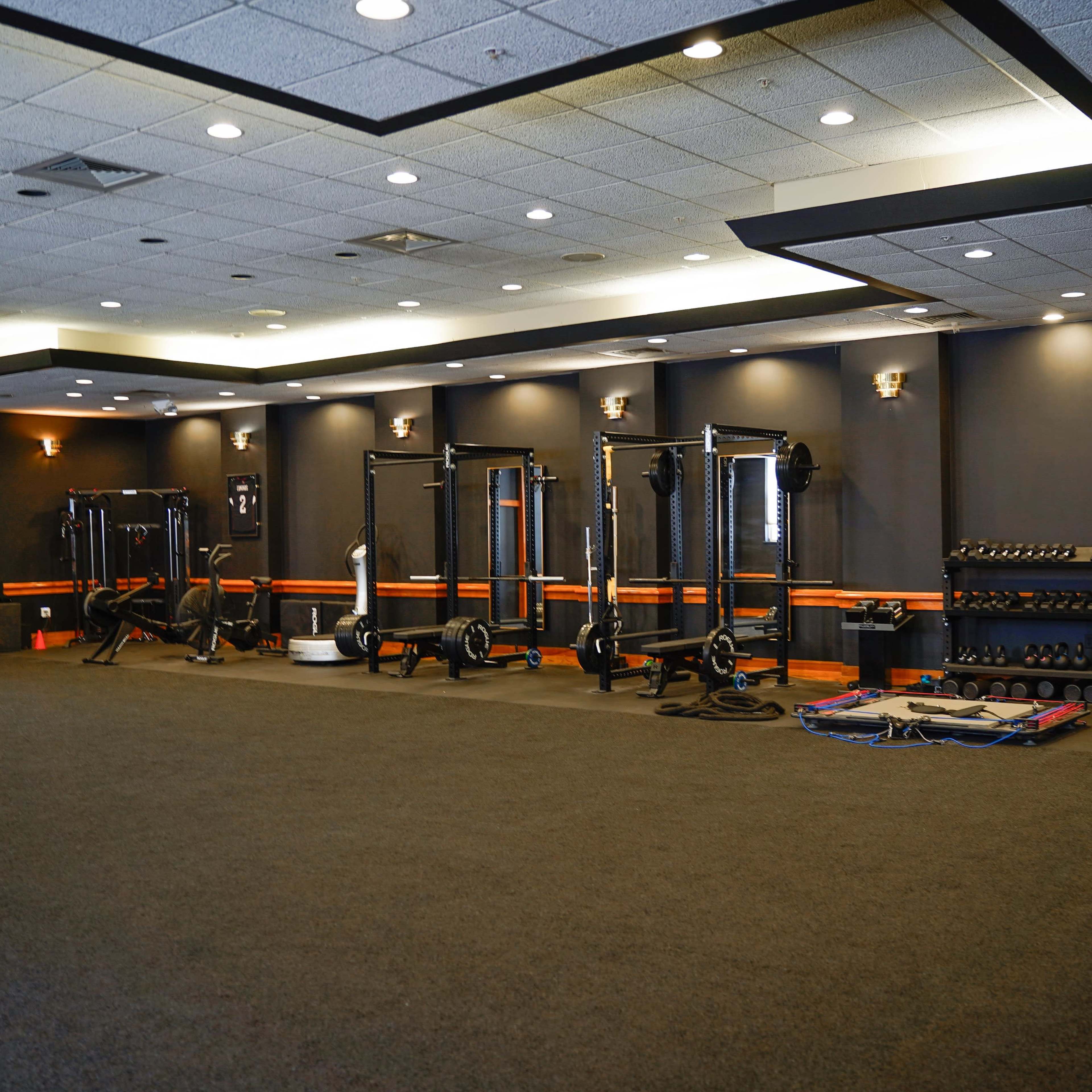 A fitness facility features various weightlifting and conditioning equipment arranged along the walls.