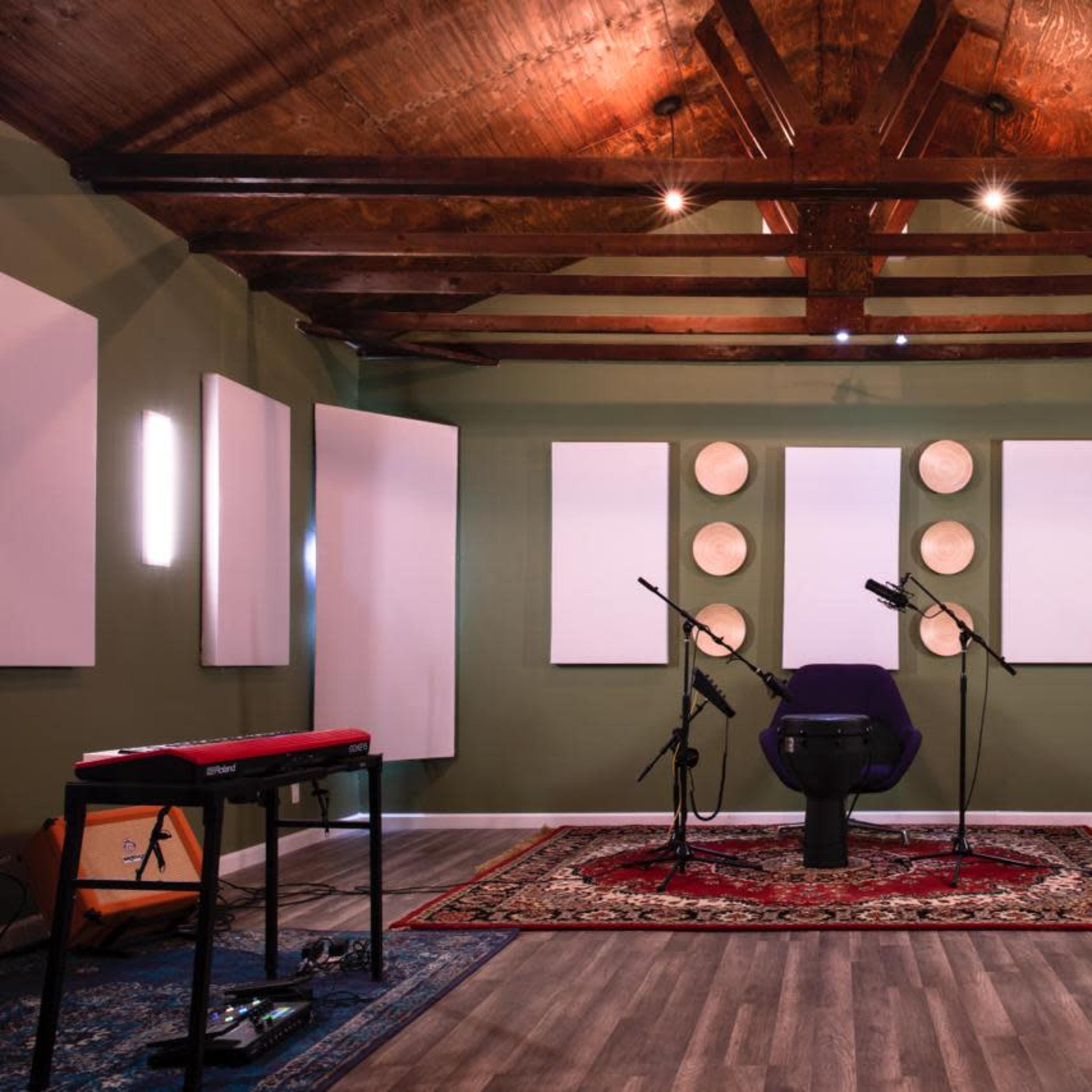 A sound studio with a purple chair, microphones, acoustic panels on the walls, and a keyboard in the foreground.