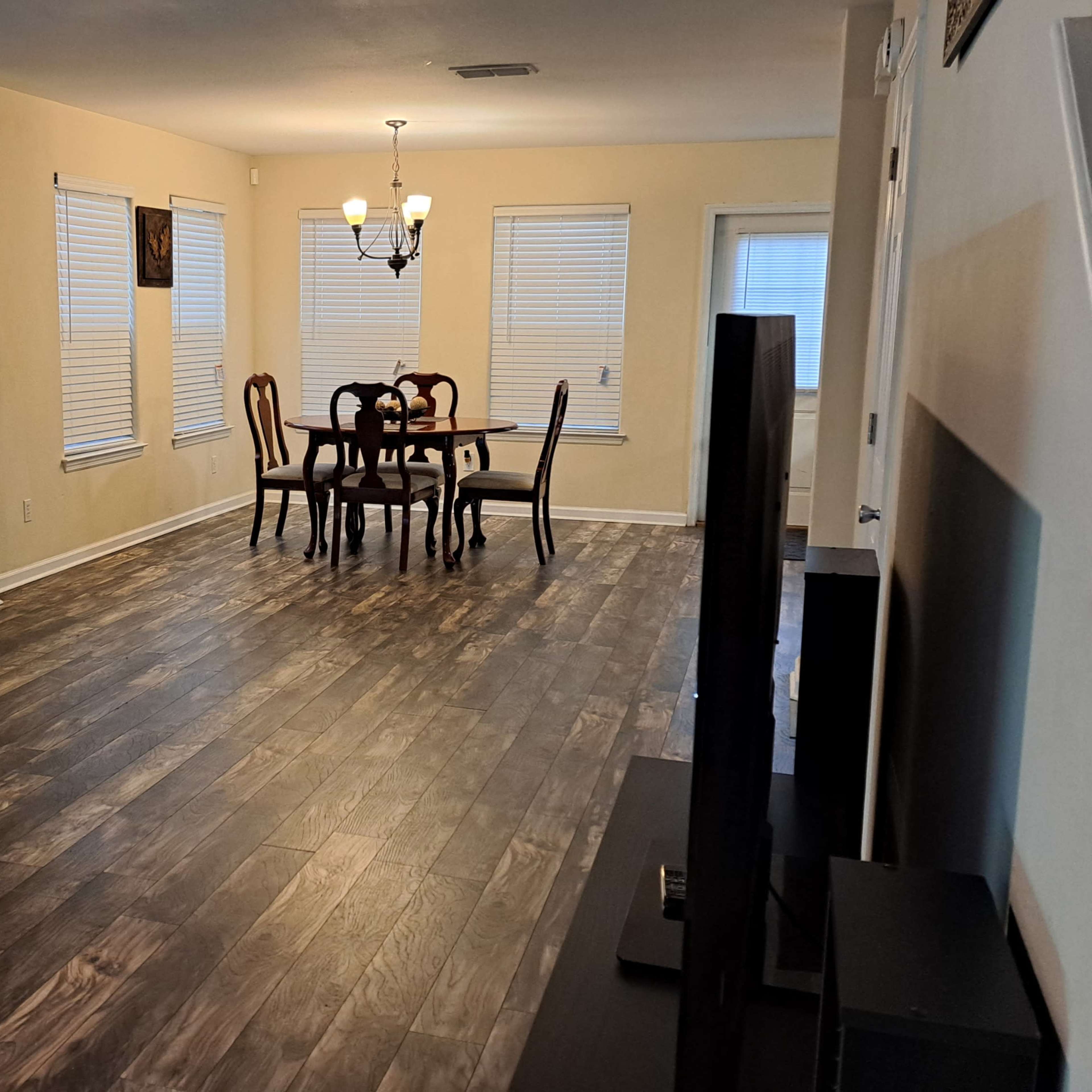 A spacious living area with a gray couch, dining table, and several windows allowing natural light.