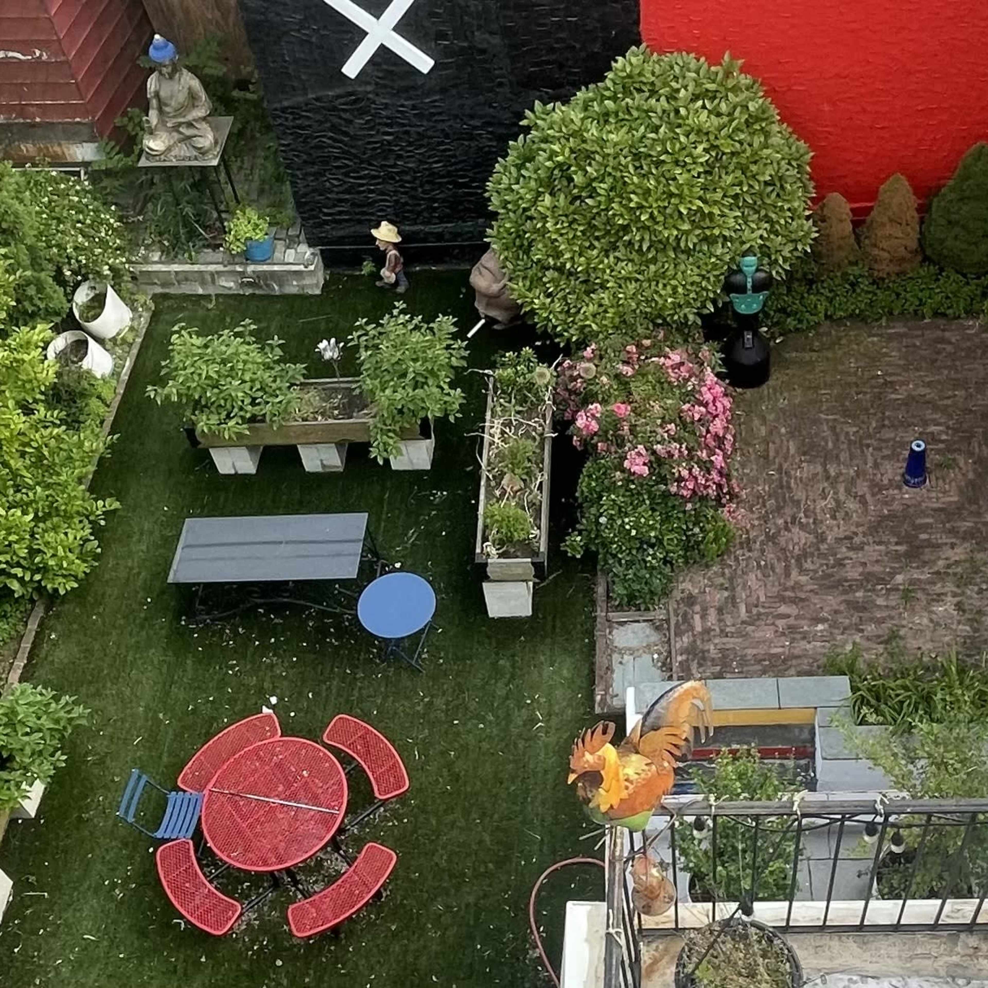 A bird's-eye view of a landscaped garden featuring tables, chairs, and various plants alongside a brick path and decorative elements.