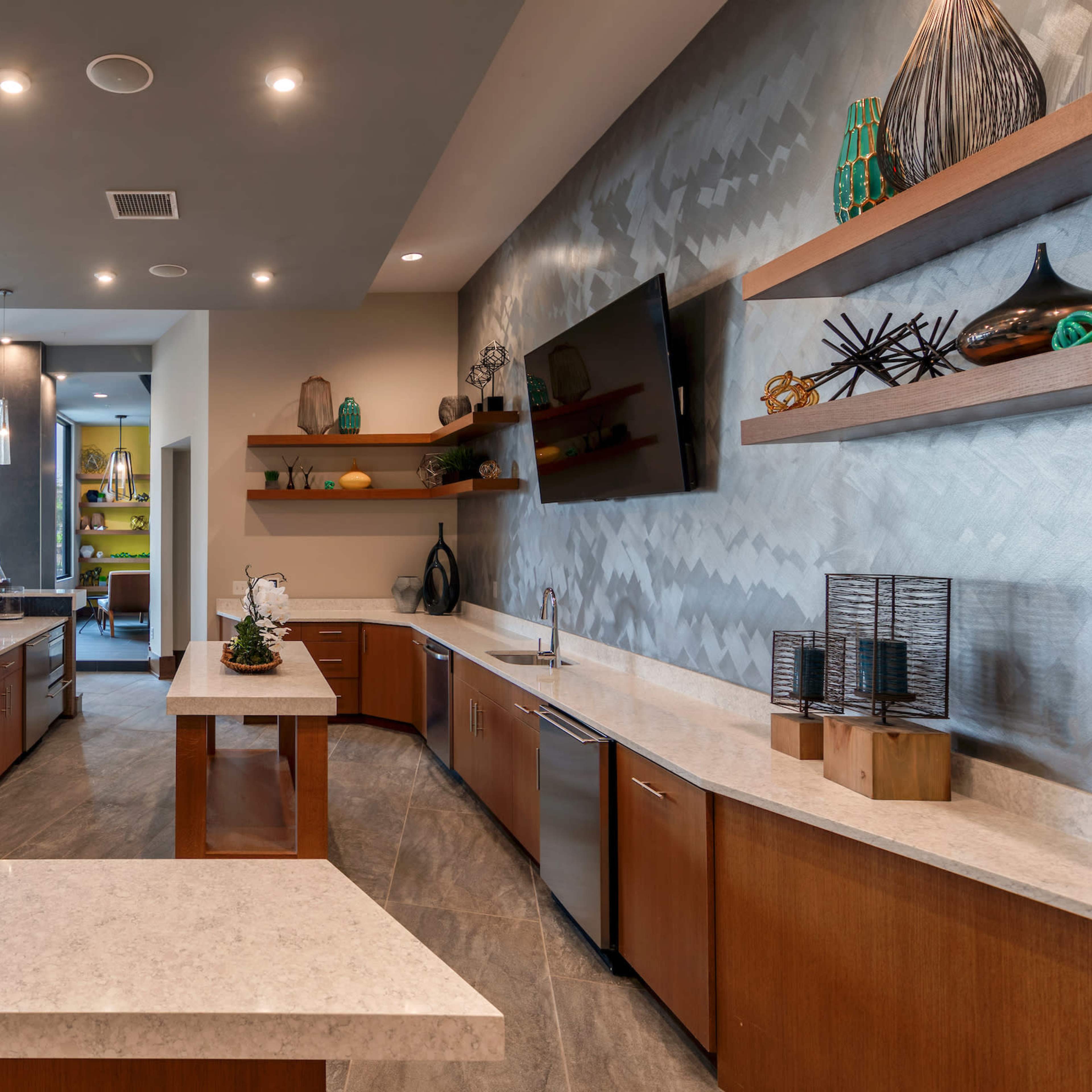 A modern kitchen area with granite countertops, wooden cabinets, and large windows overlooking an outdoor space.