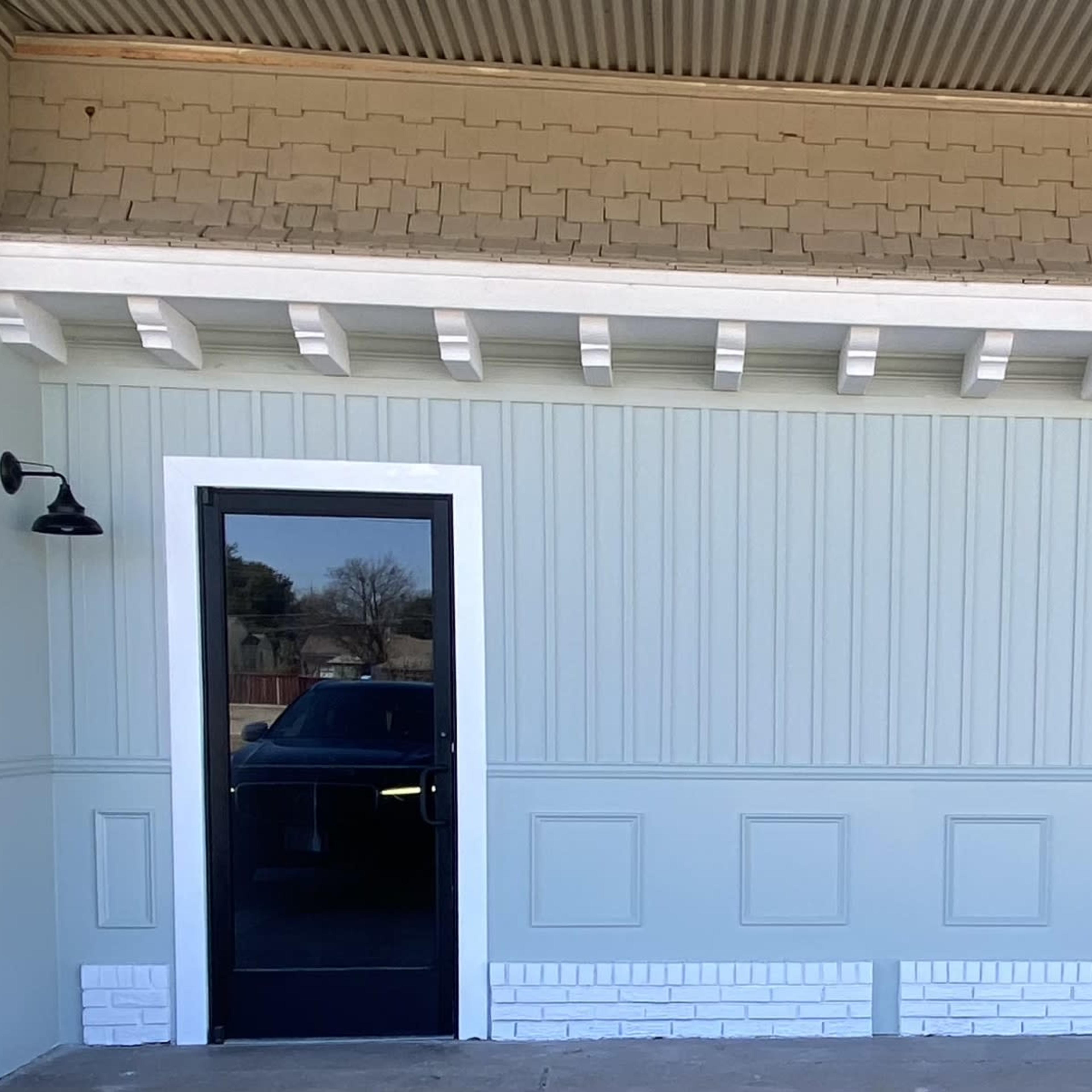 A light blue paneled wall with a black door and two wall-mounted lights on either side.