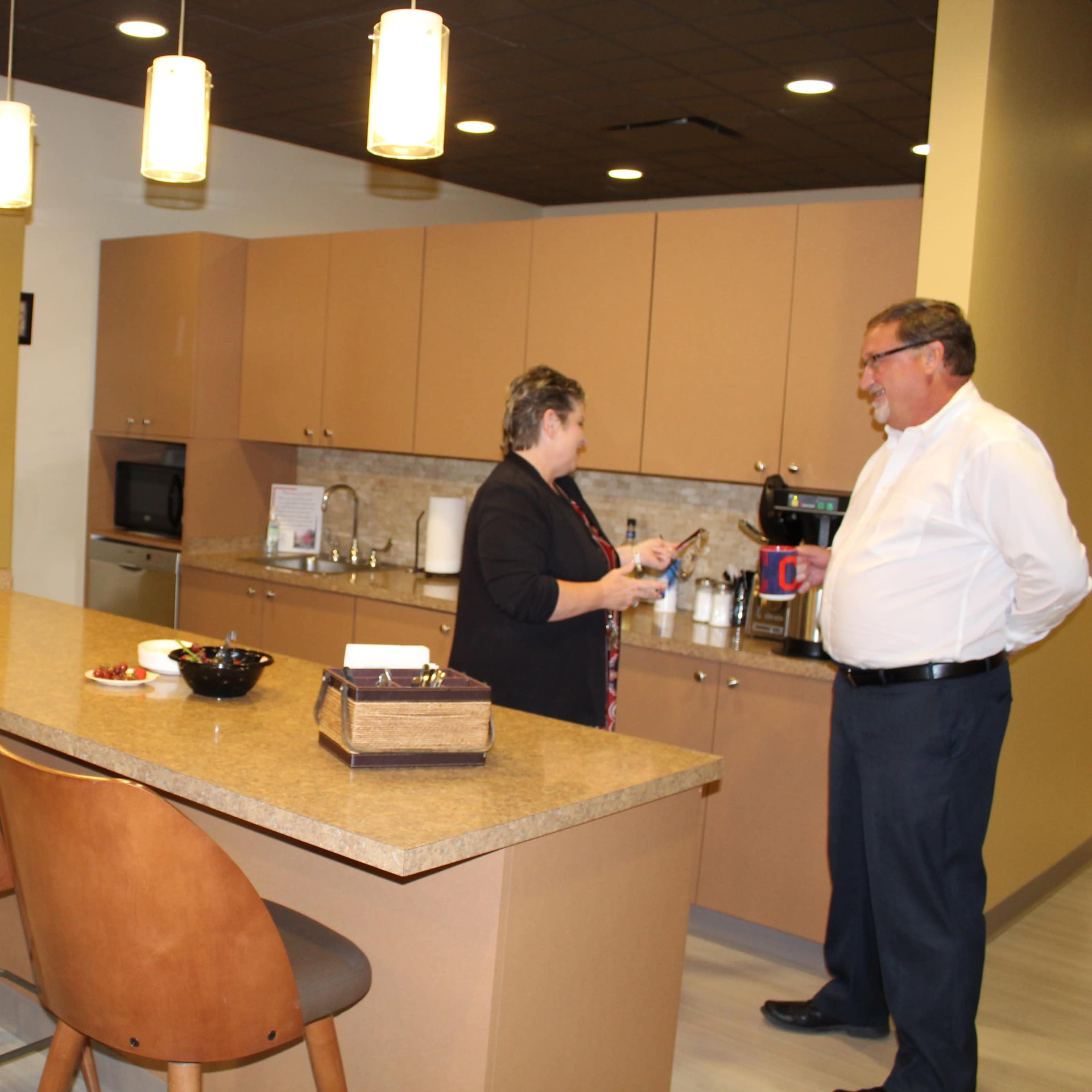 A modern kitchen with a central island, equipped with bar stools, where two people are engaged in conversation.