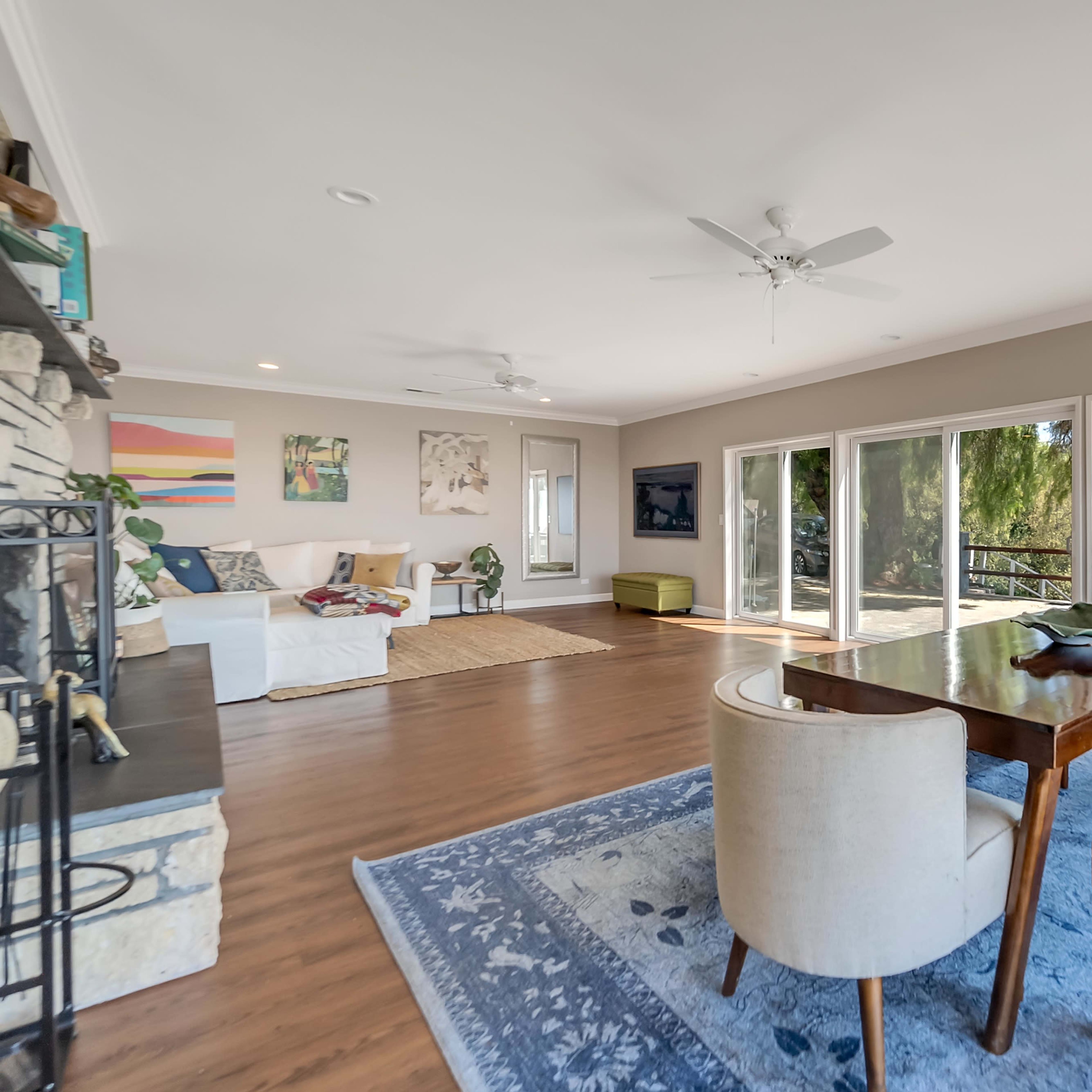 An open living area with a wooden dining table and chairs, large windows providing a view, and a comfortable seating arrangement.