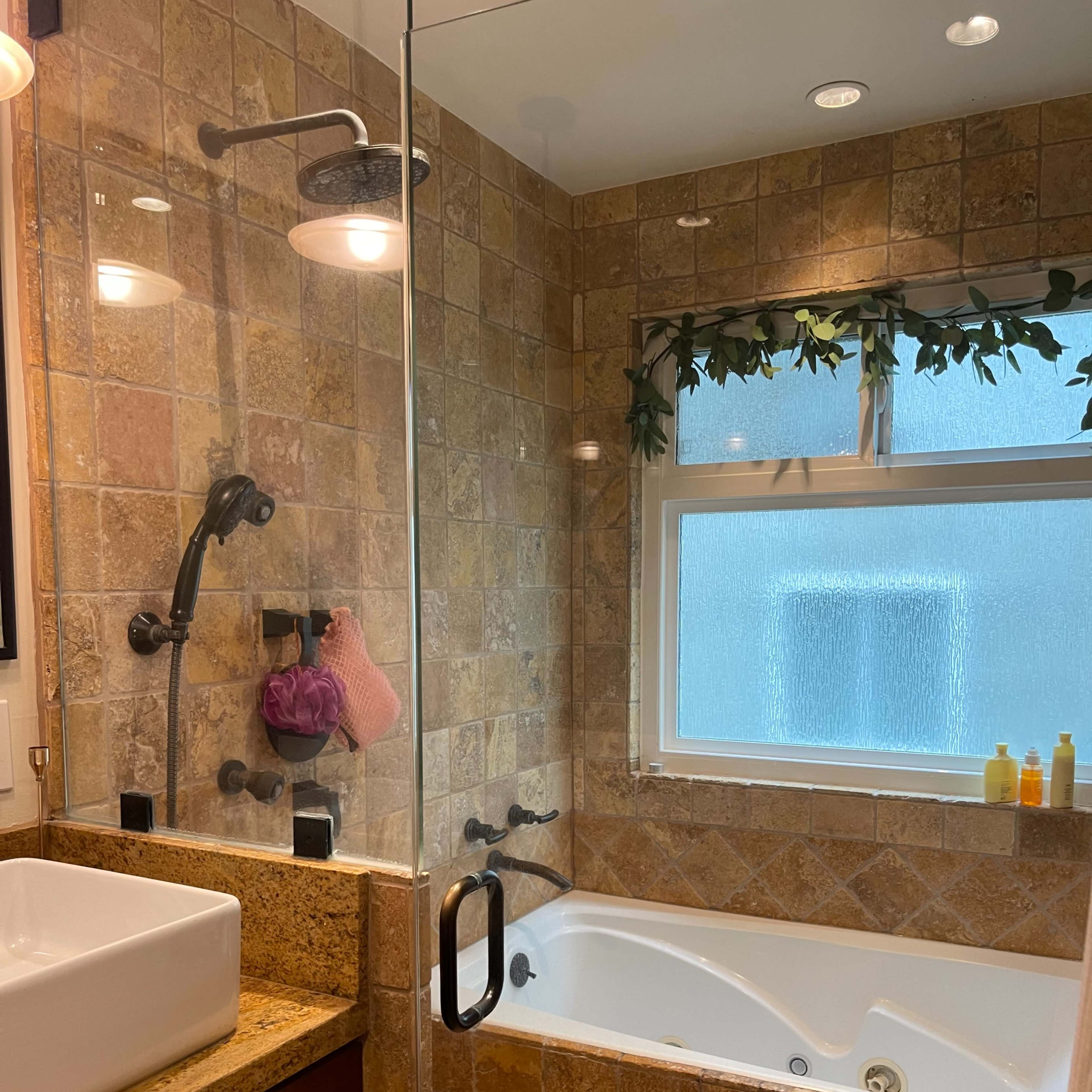 A bathroom featuring a glass-enclosed shower, a bathtub with a jets system, and stone tiled walls.