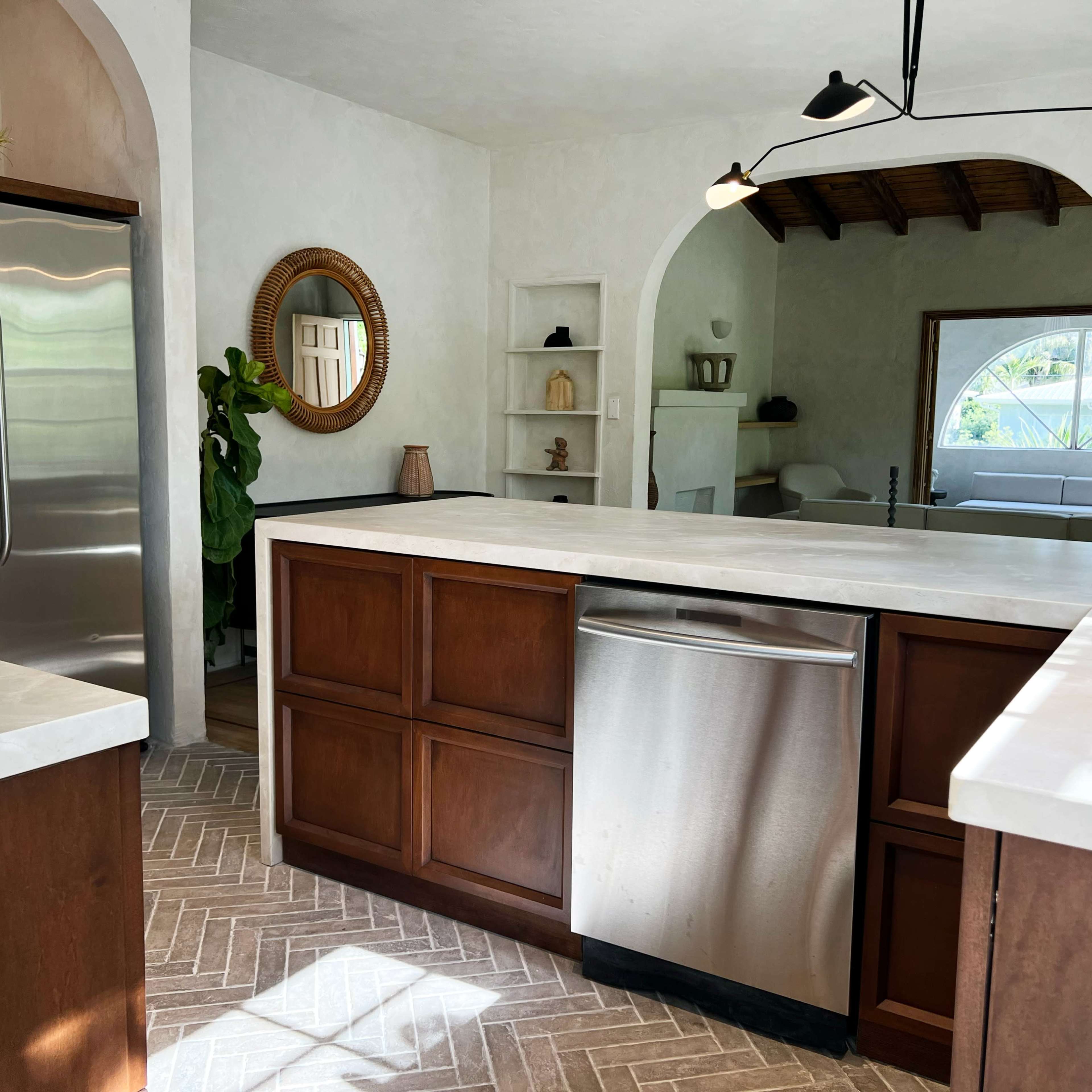 A modern kitchen with wooden cabinets, stainless steel appliances, and a large island featuring a light-colored countertop.