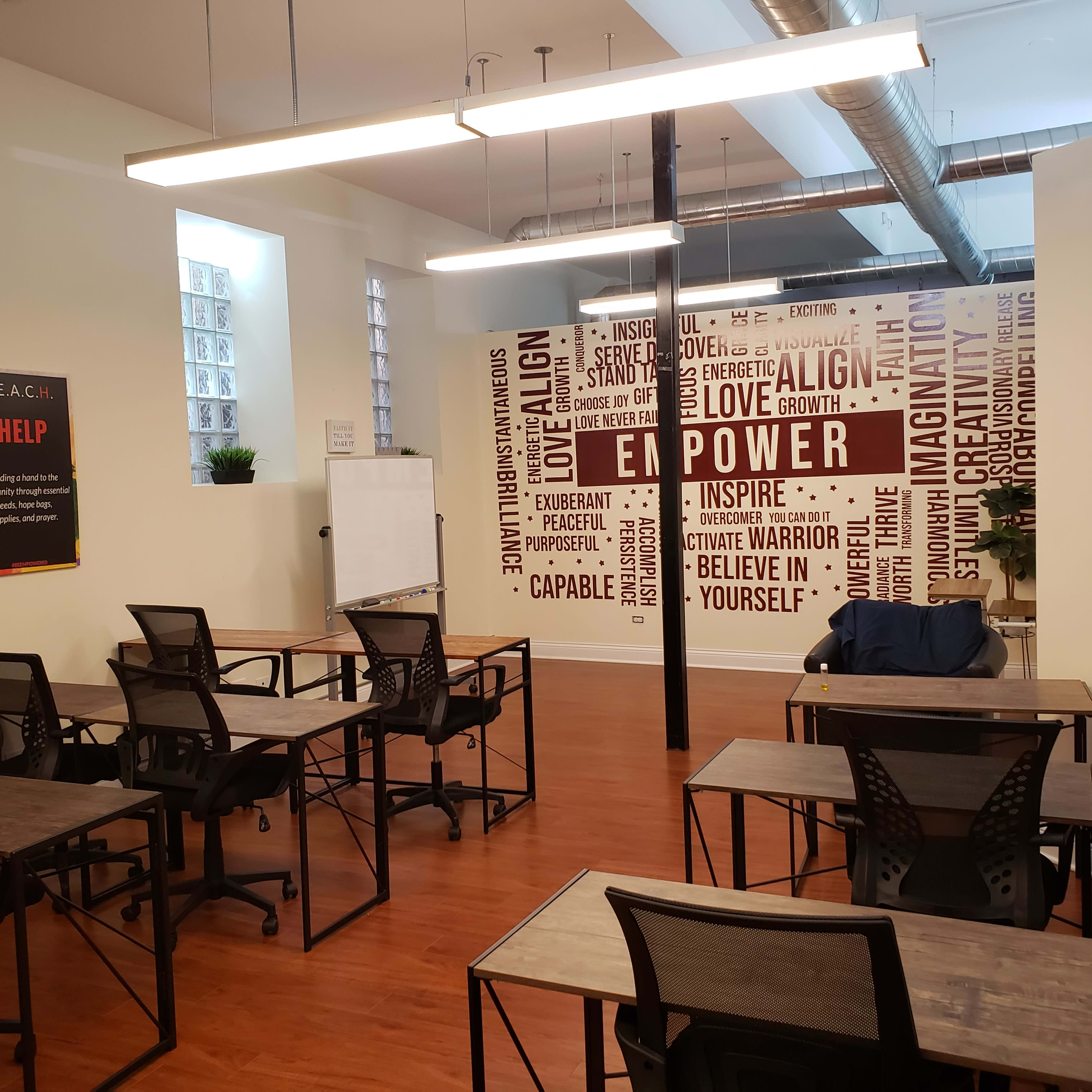 A training room with several empty desks and chairs arranged in front of a wall covered in motivational words and phrases.