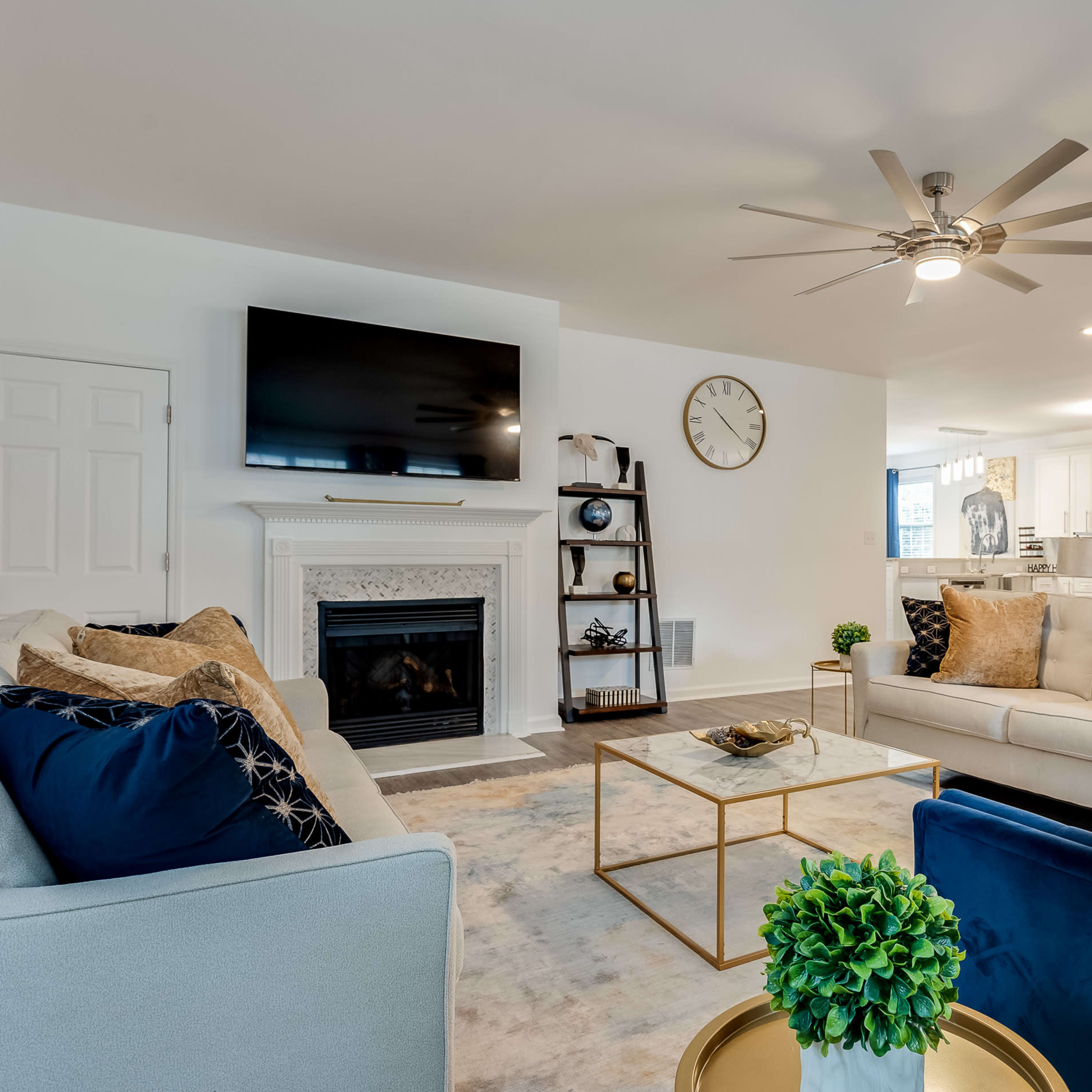 The living room features a fireplace with a television above it, surrounded by two sofas, a coffee table, and decorative elements.