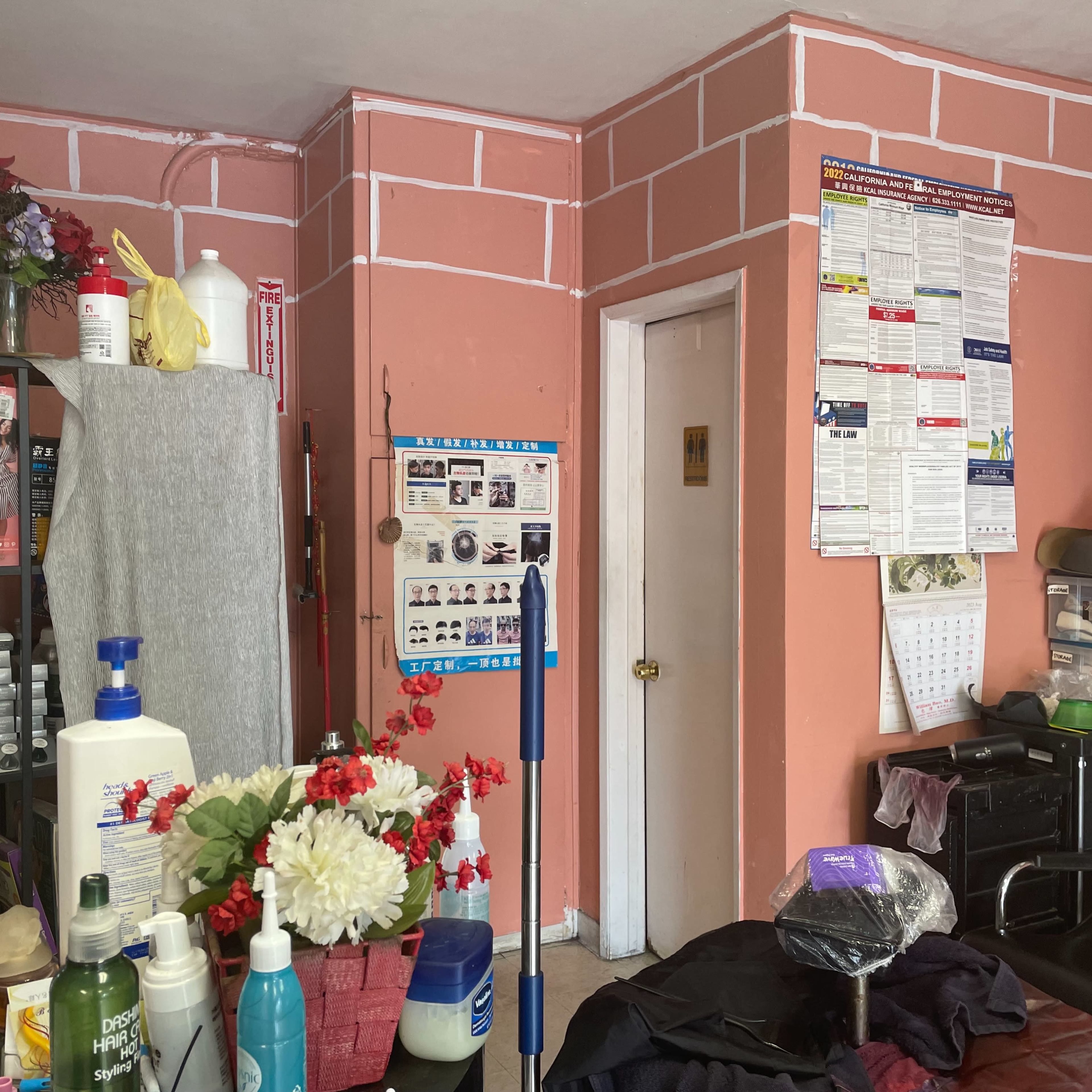 A room with pink walls, shelves filled with various bottles and products, and a door leading to another area.