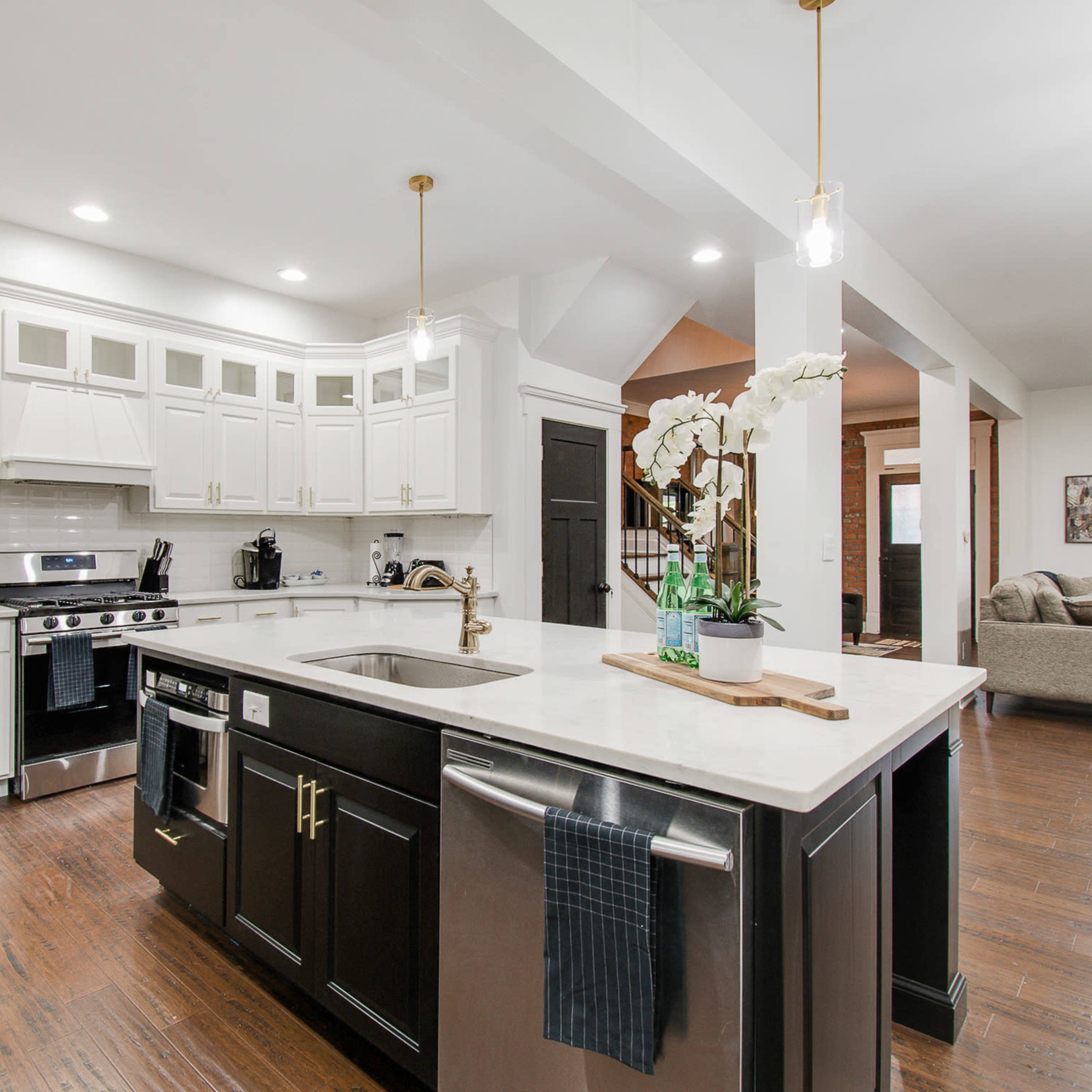 A modern kitchen featuring white cabinetry, stainless steel appliances, and an island with a dark countertop.