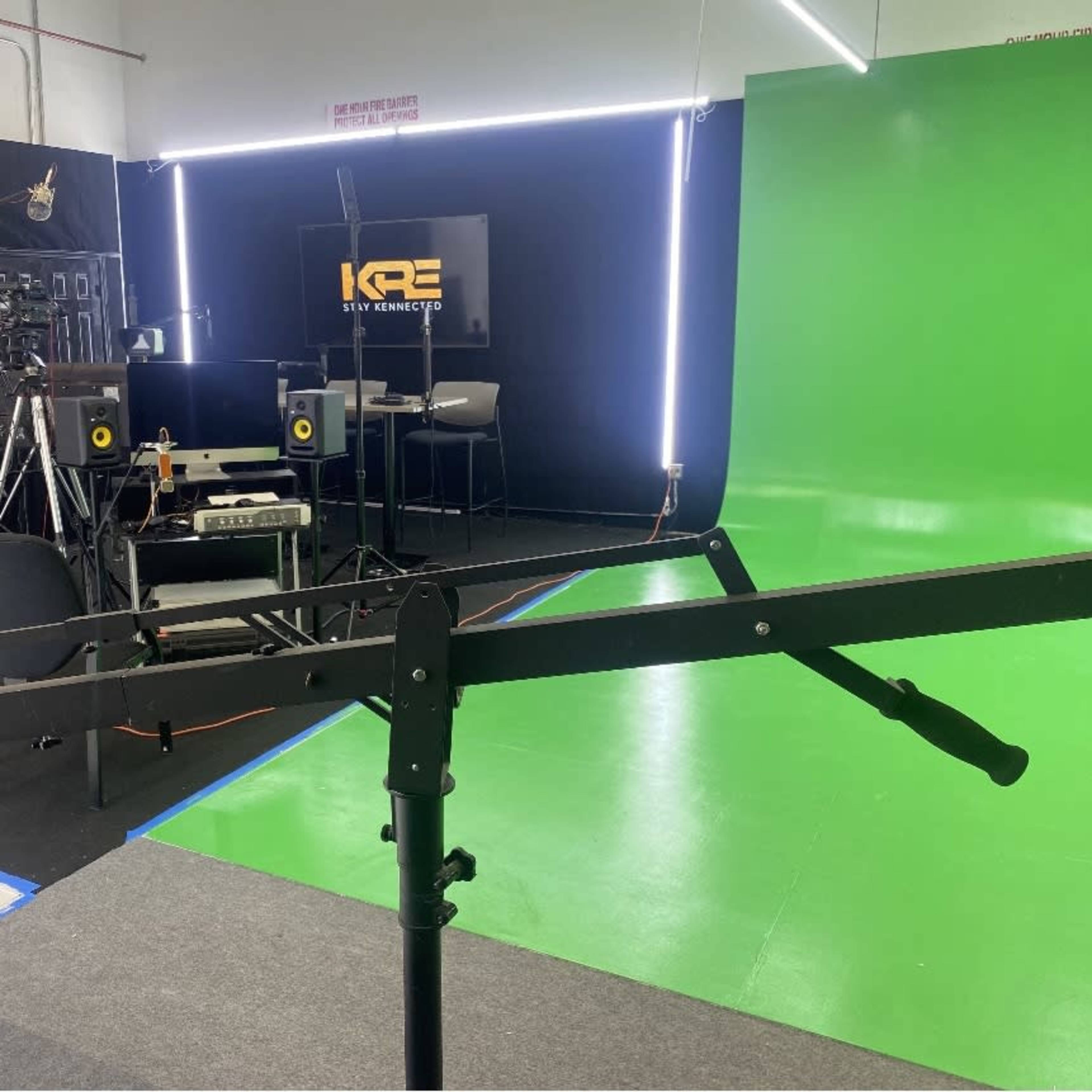 A studio setup featuring a green screen, cameras, lighting equipment, and a computer workstation.