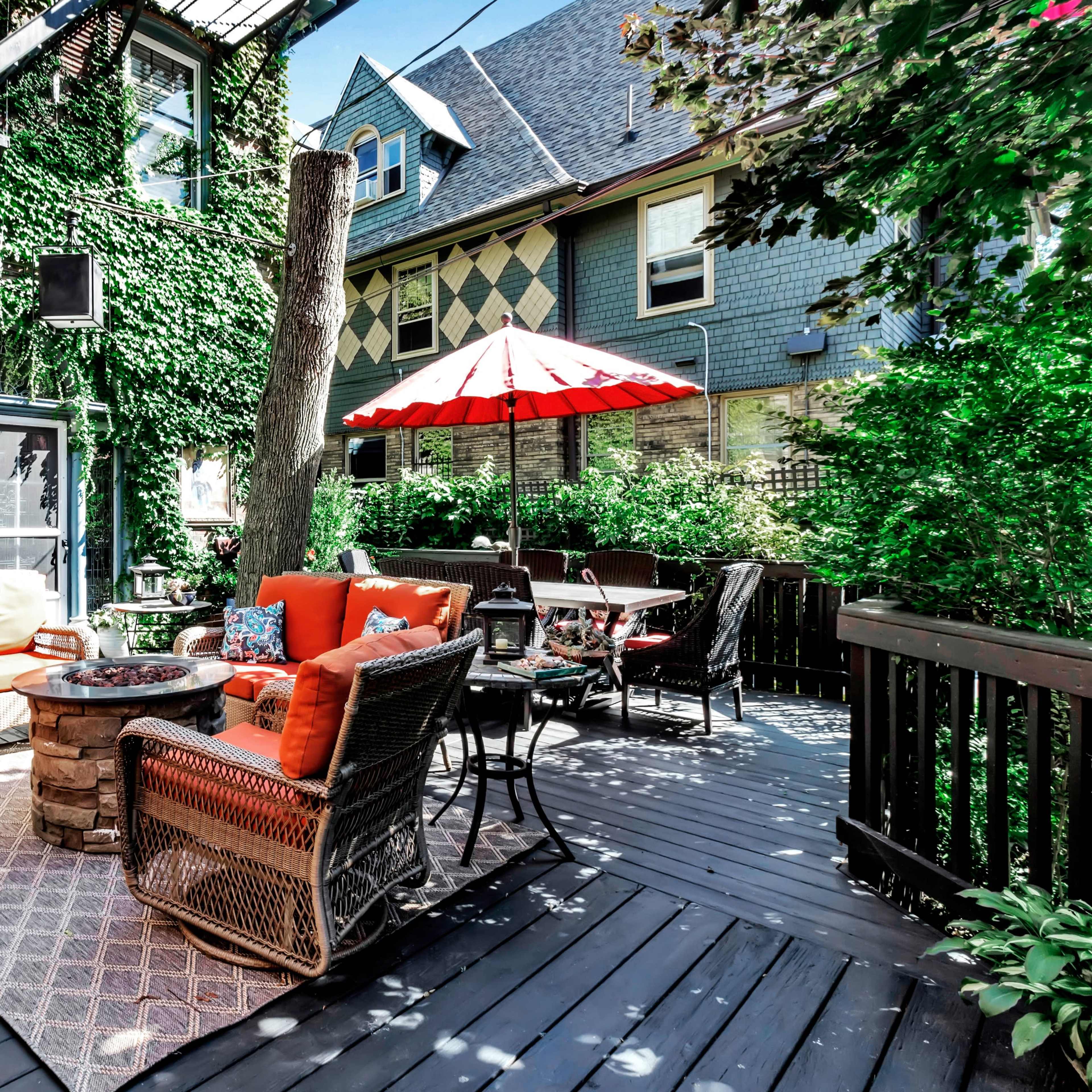 A large brick house with a front porch, surrounded by well-maintained gardens and trees.
