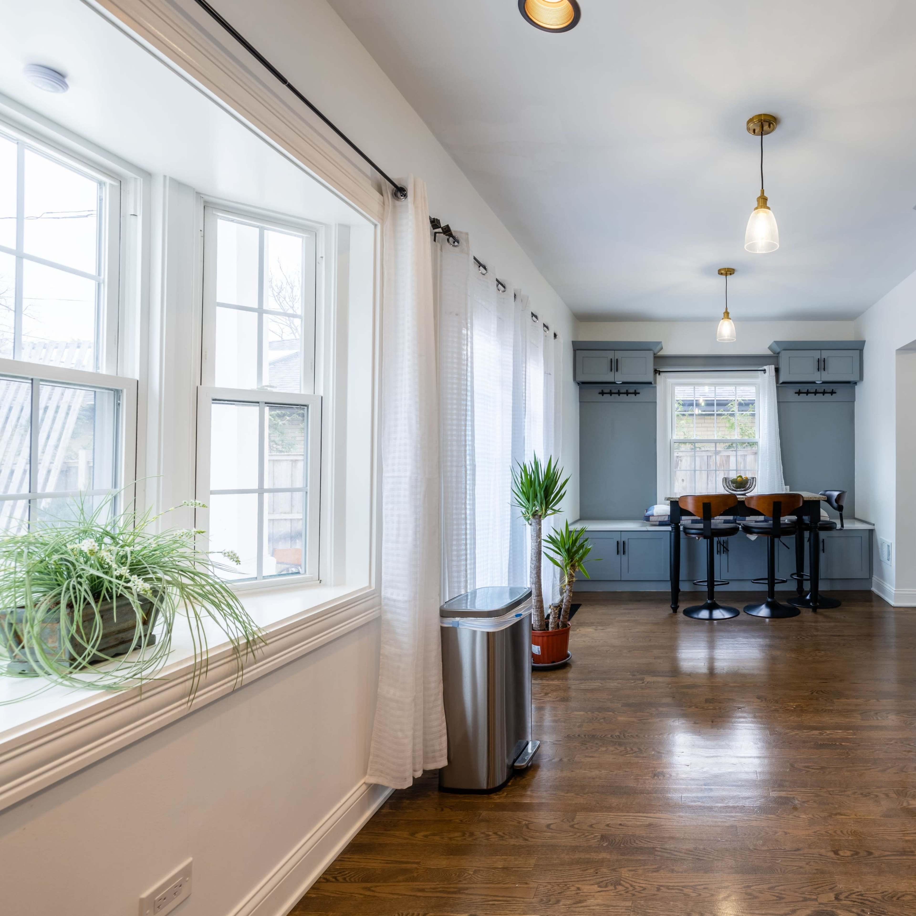 A well-lit kitchen features gray cabinets, stainless steel appliances, and a small dining area with a round table and chairs by the window.