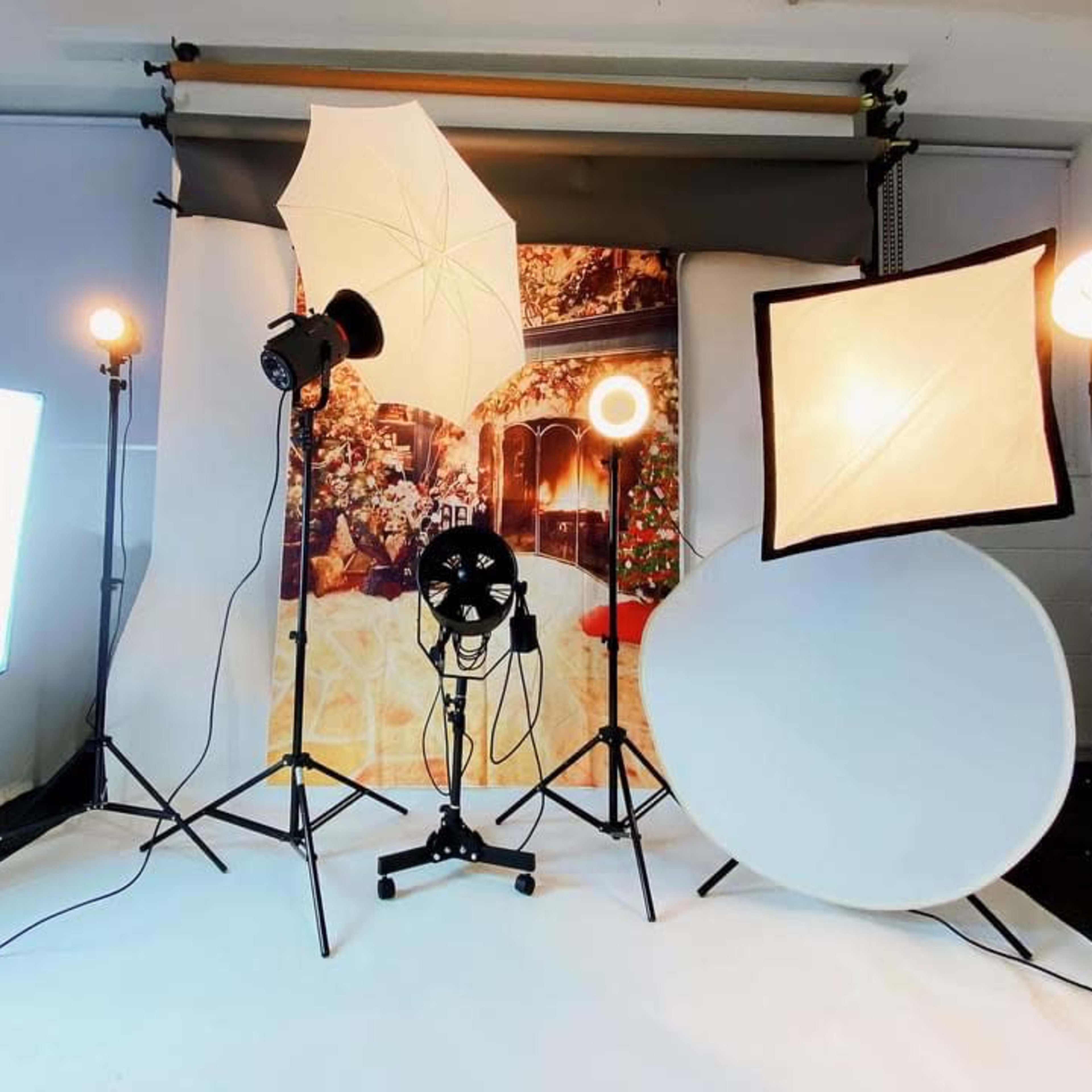 A photography studio setup with various lights and reflectors arranged around a backdrop featuring a decorative scene.
