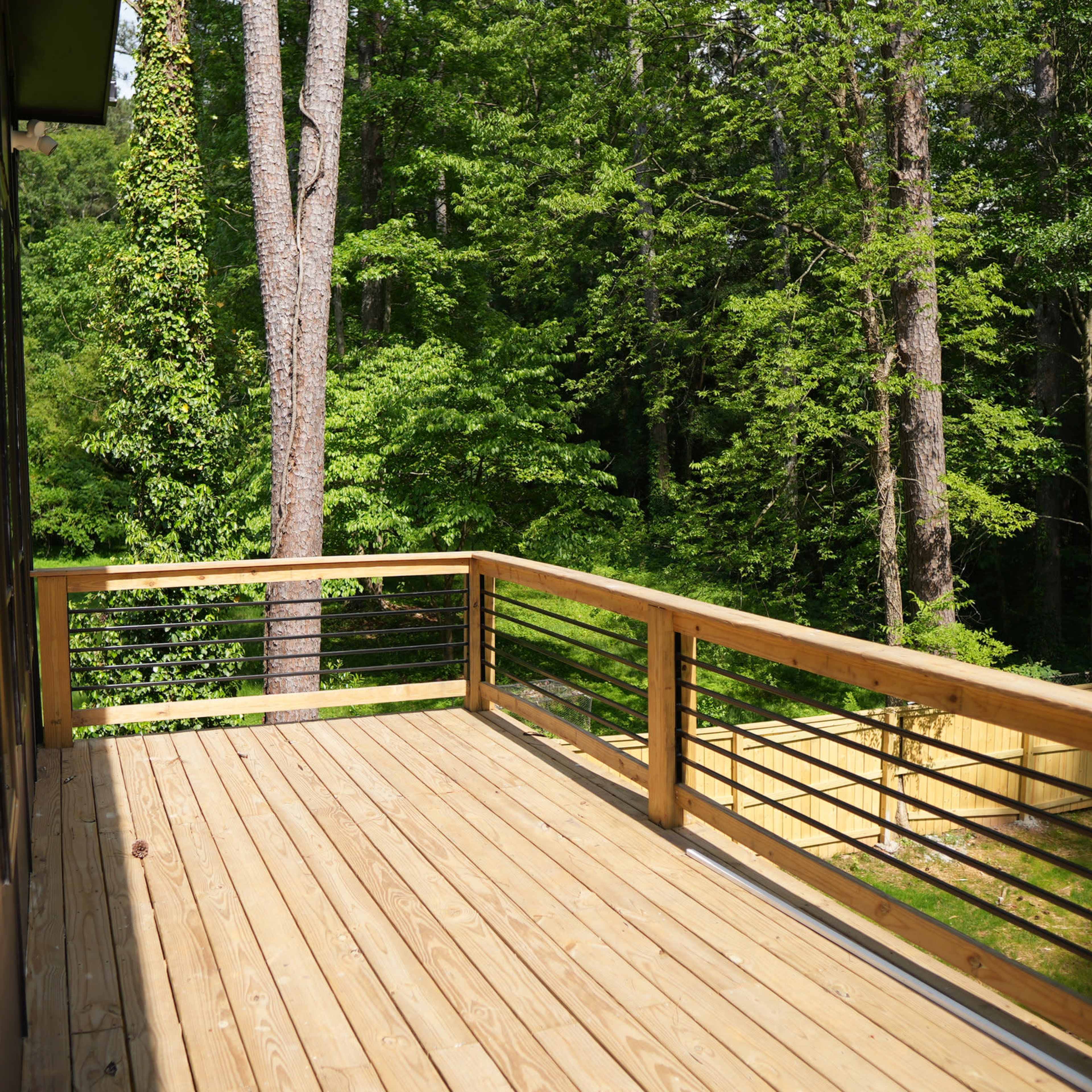 A wooden deck extending into a wooded area with trees in the background.