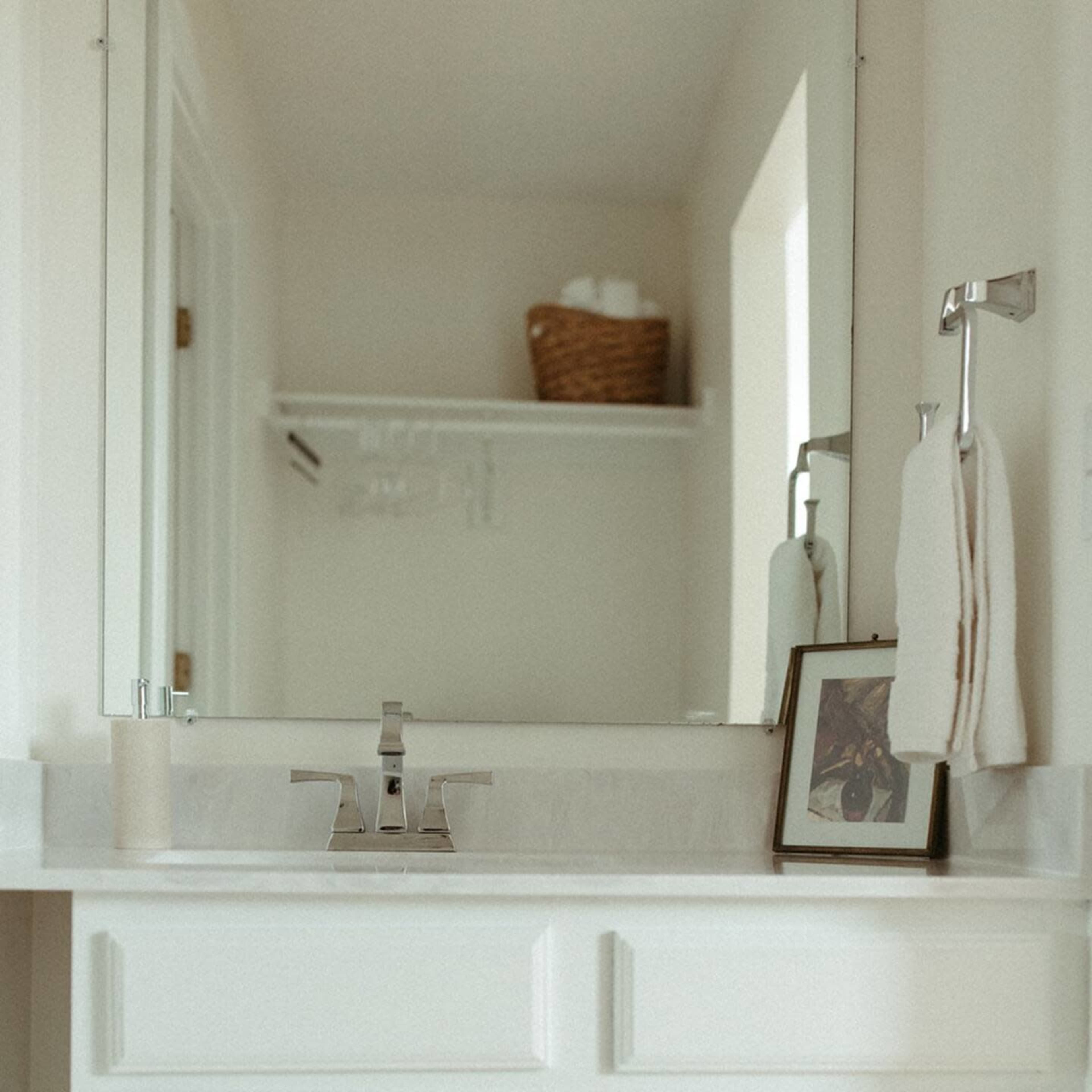 A clean, modern bathroom vanity with a sink, mirror, and neatly organized towels.