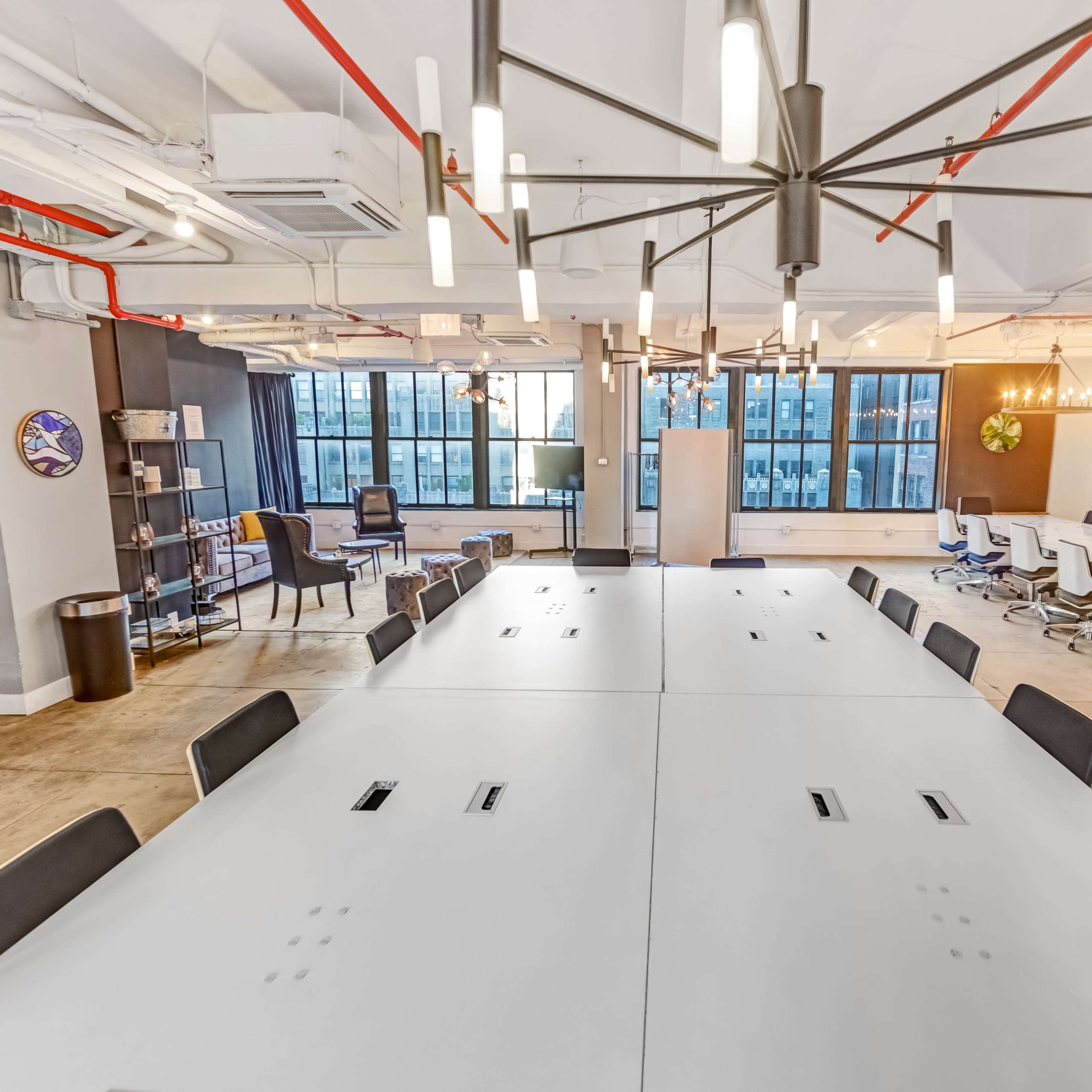 A spacious, modern conference room features a large, white table surrounded by chairs and large windows showing an urban skyline.