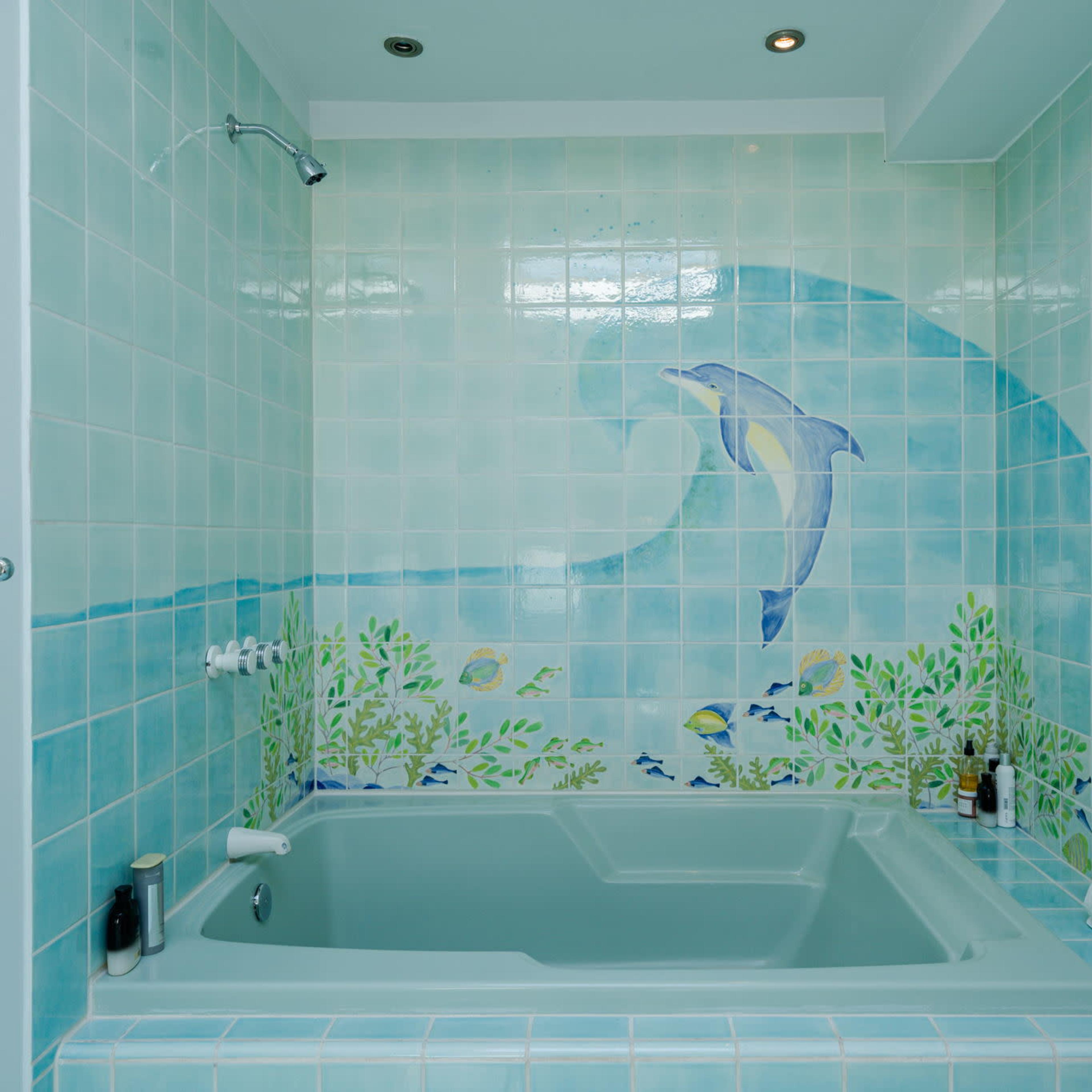 The bathroom features a light-colored bathtub surrounded by decorative tiles depicting marine life.
